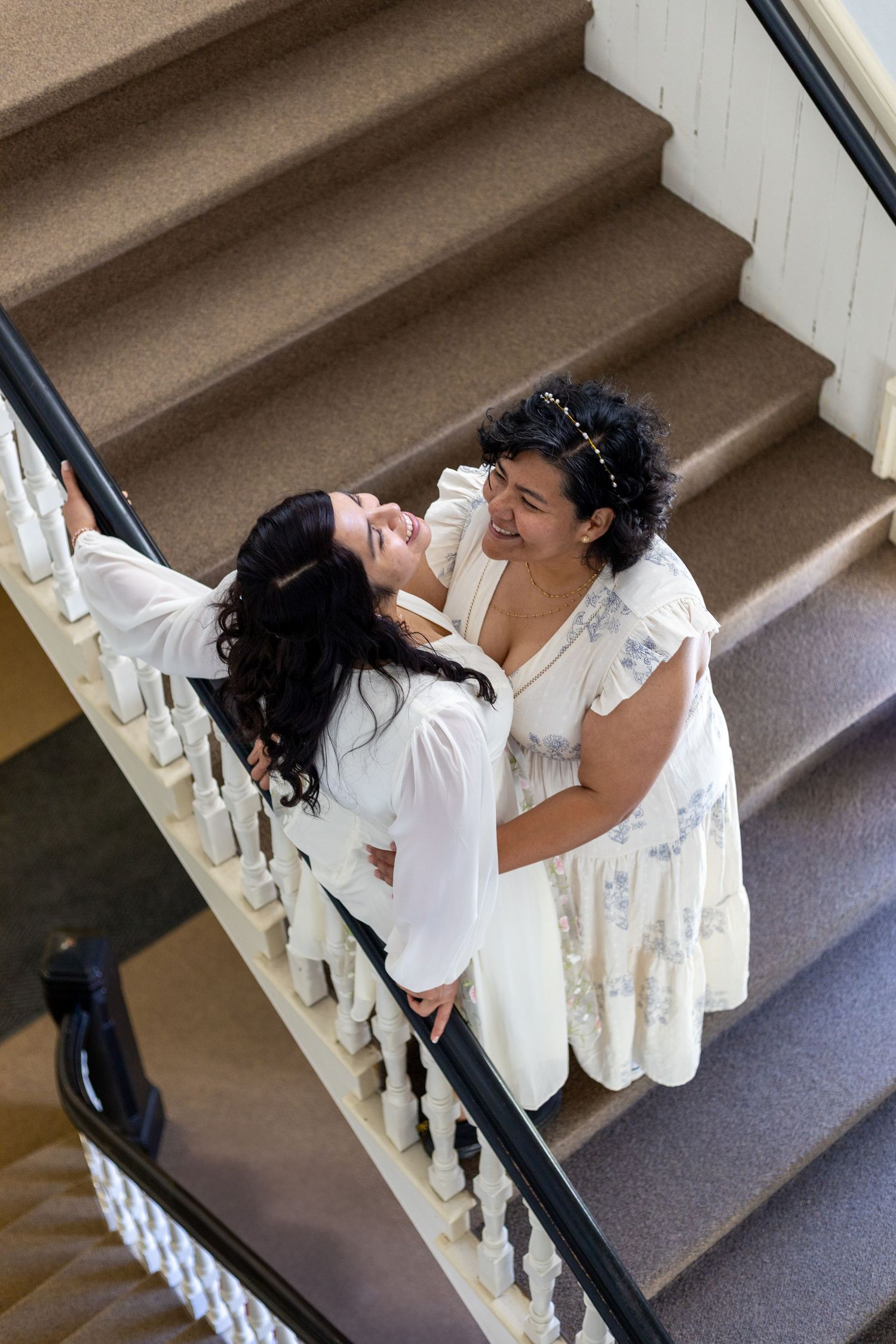 Couple sharing intimate moment on elegant white staircase.