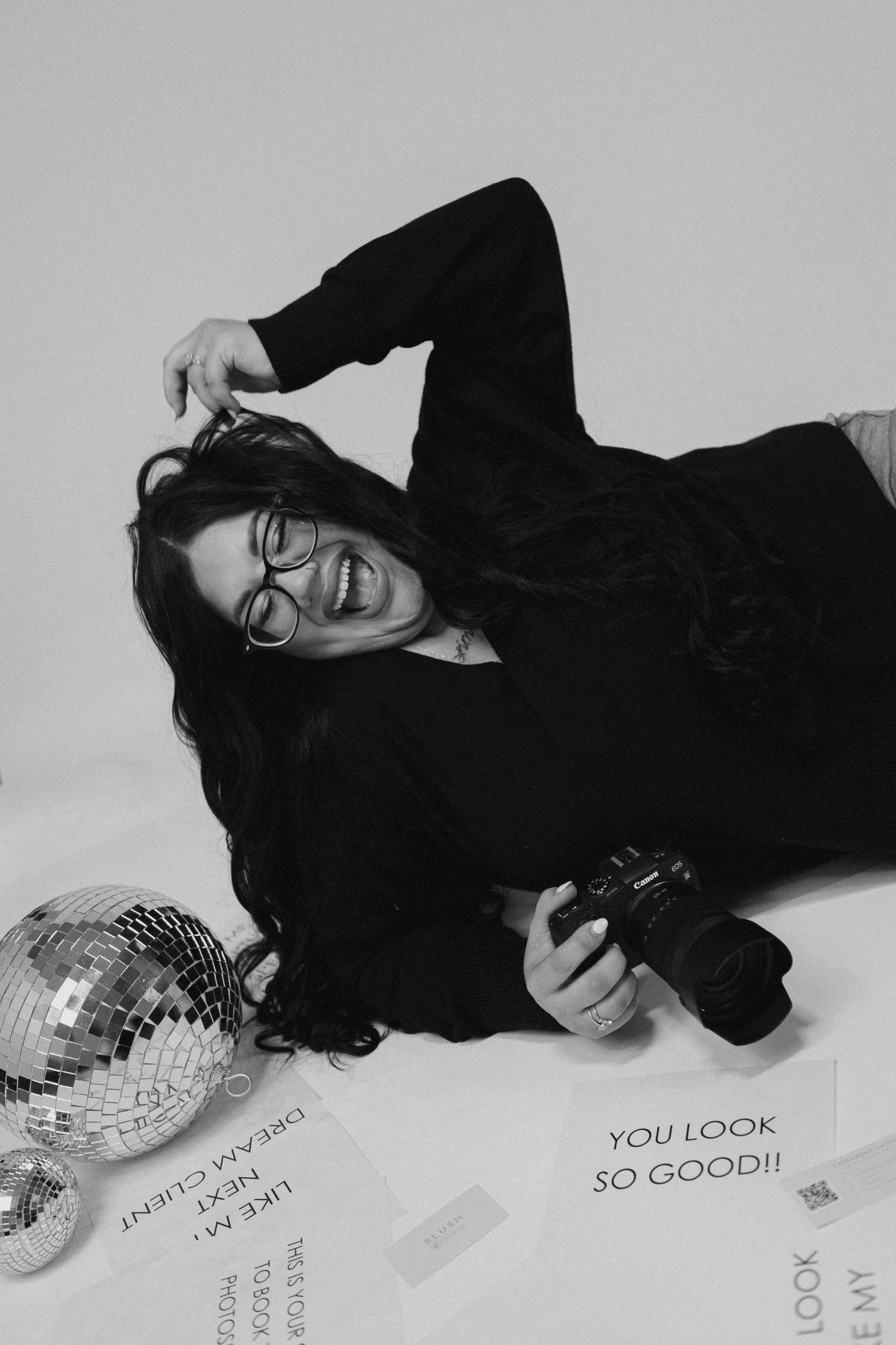 Person in black lying next to disco ball in artistic black and white photo series.