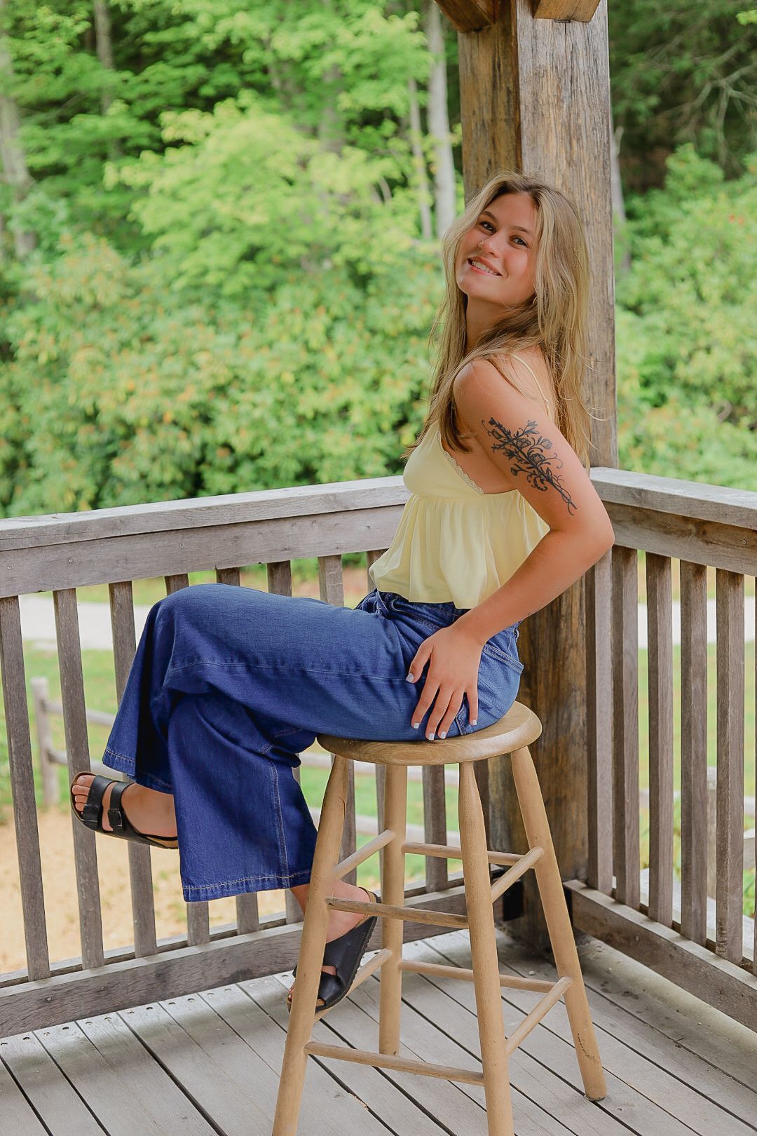 Casual photoshoot on a wooden deck with rustic wooden chairs.