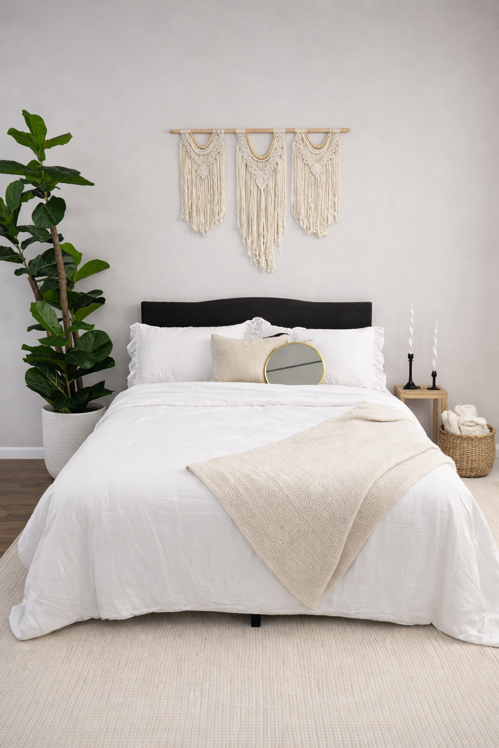 Serene white bedroom featuring macrame wall art, lush fiddle leaf fig, and neutral textured bedding.