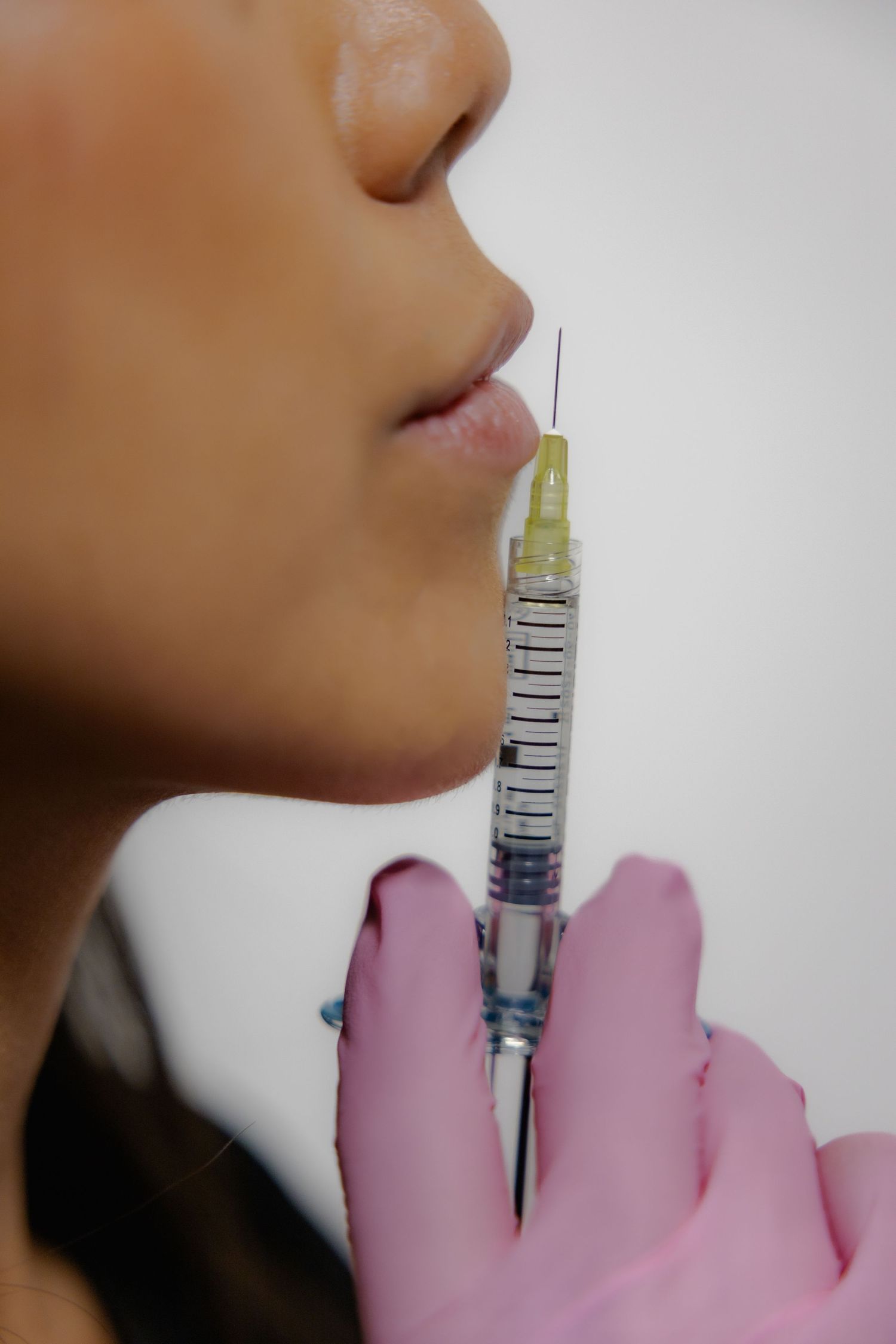 Close-up view of a medical injection being administered with pink gloved hands.