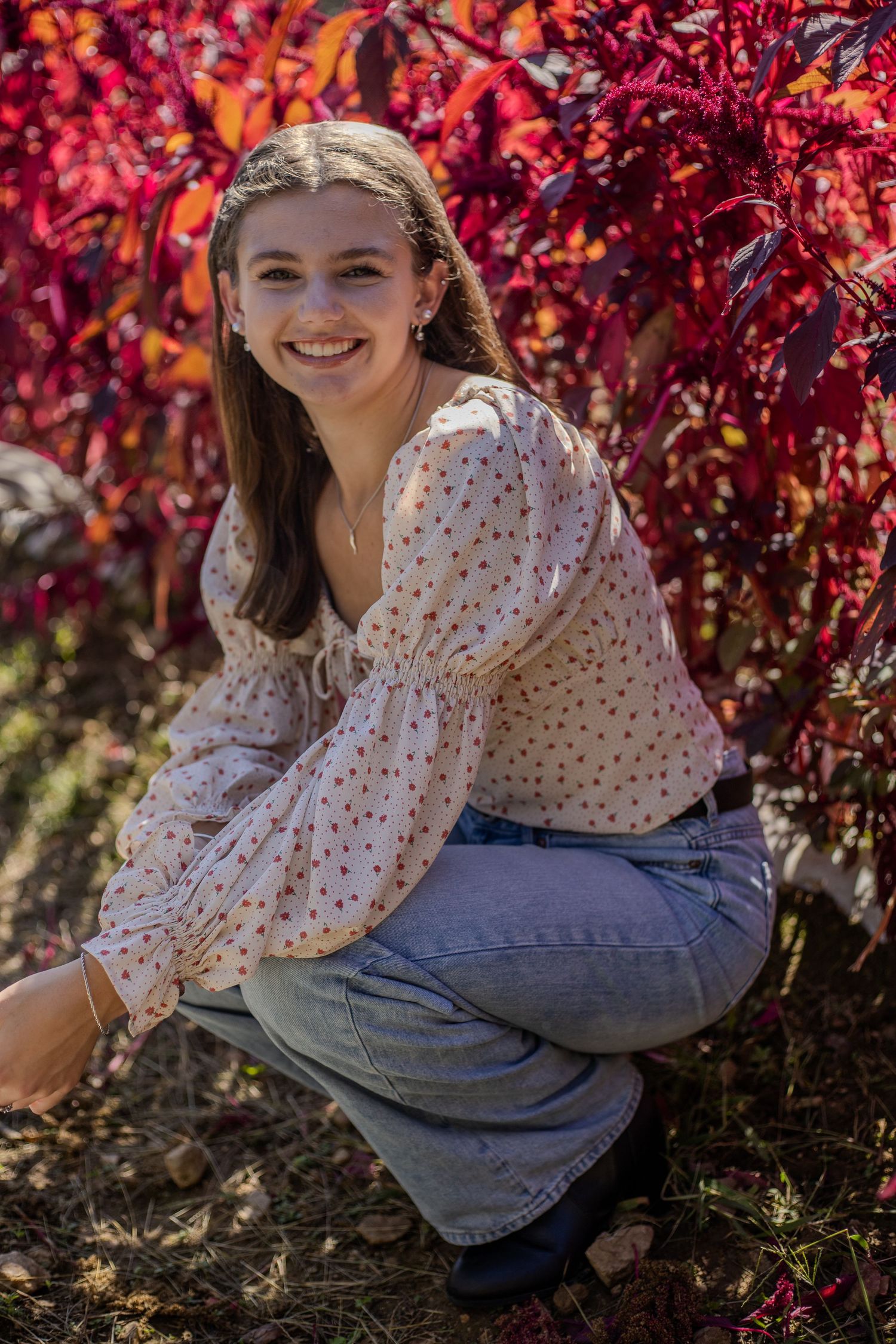 Outdoor portrait session with red autumn foliage and polka dot blouse.