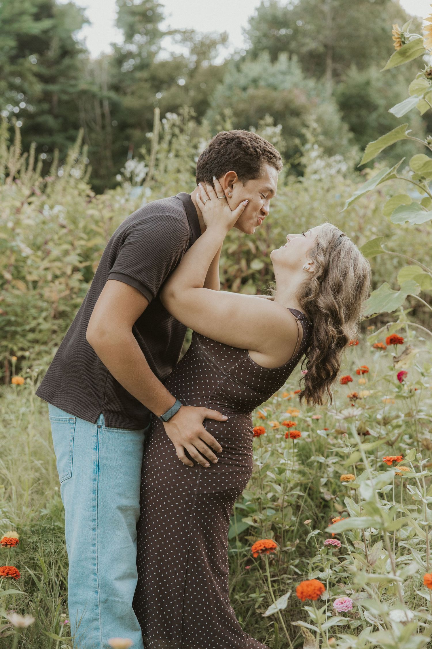 Romantic couple sharing a kiss in a lush garden surrounded by colorful blooms.