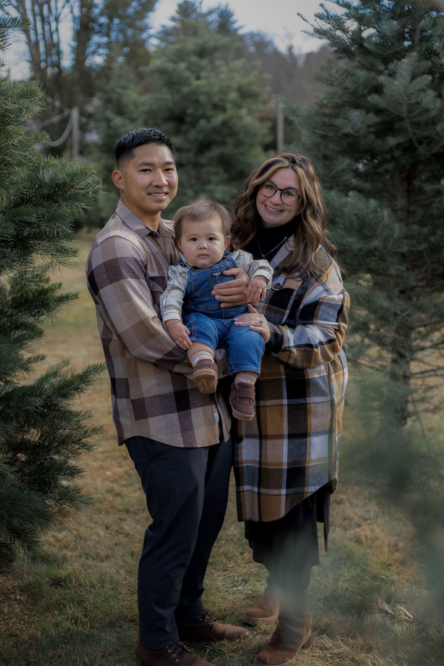 A family shares tender moments among evergreen trees during an outdoor photo session.