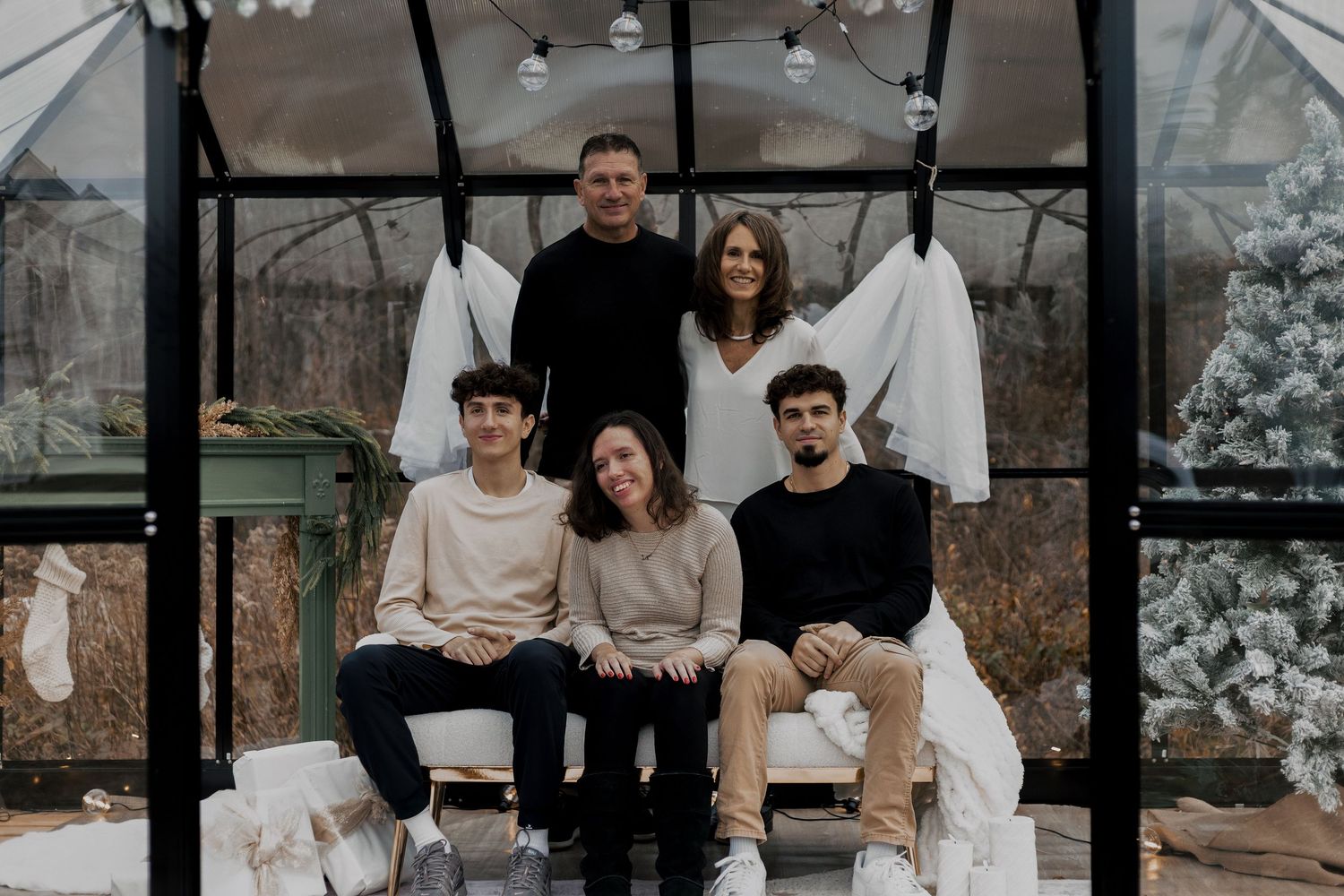 A group sits casually together on wooden steps with winter decorations.