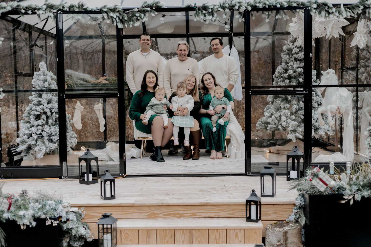 Family photo session on rustic bench with white fabric draping and lantern decorations.