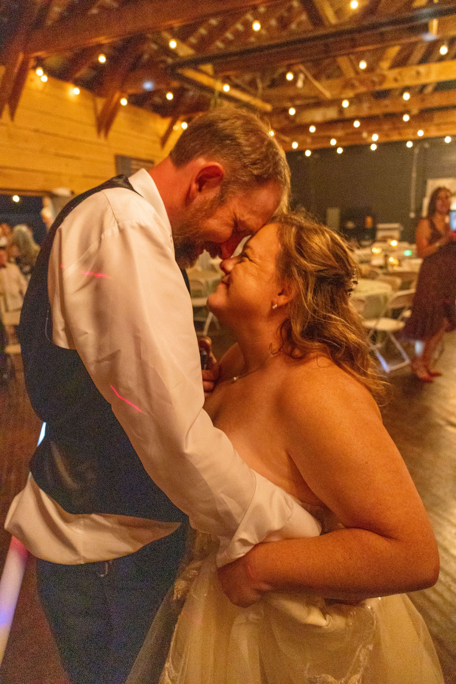 A romantic dance moment under warm lighting at an indoor wedding reception.