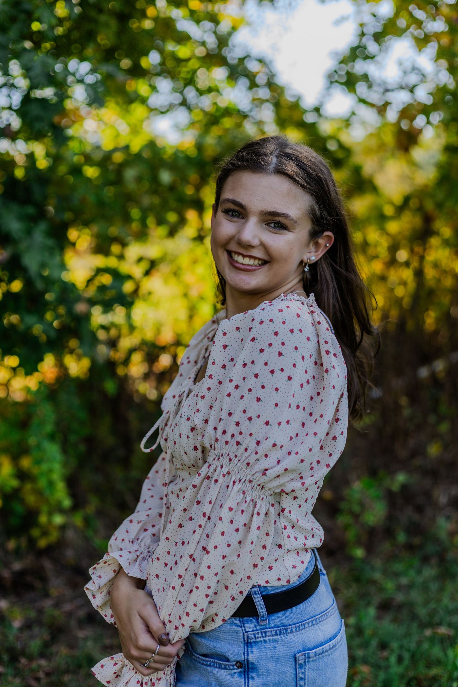 Natural outdoor portraits with greenery and polka dot blouse in sunlit setting.