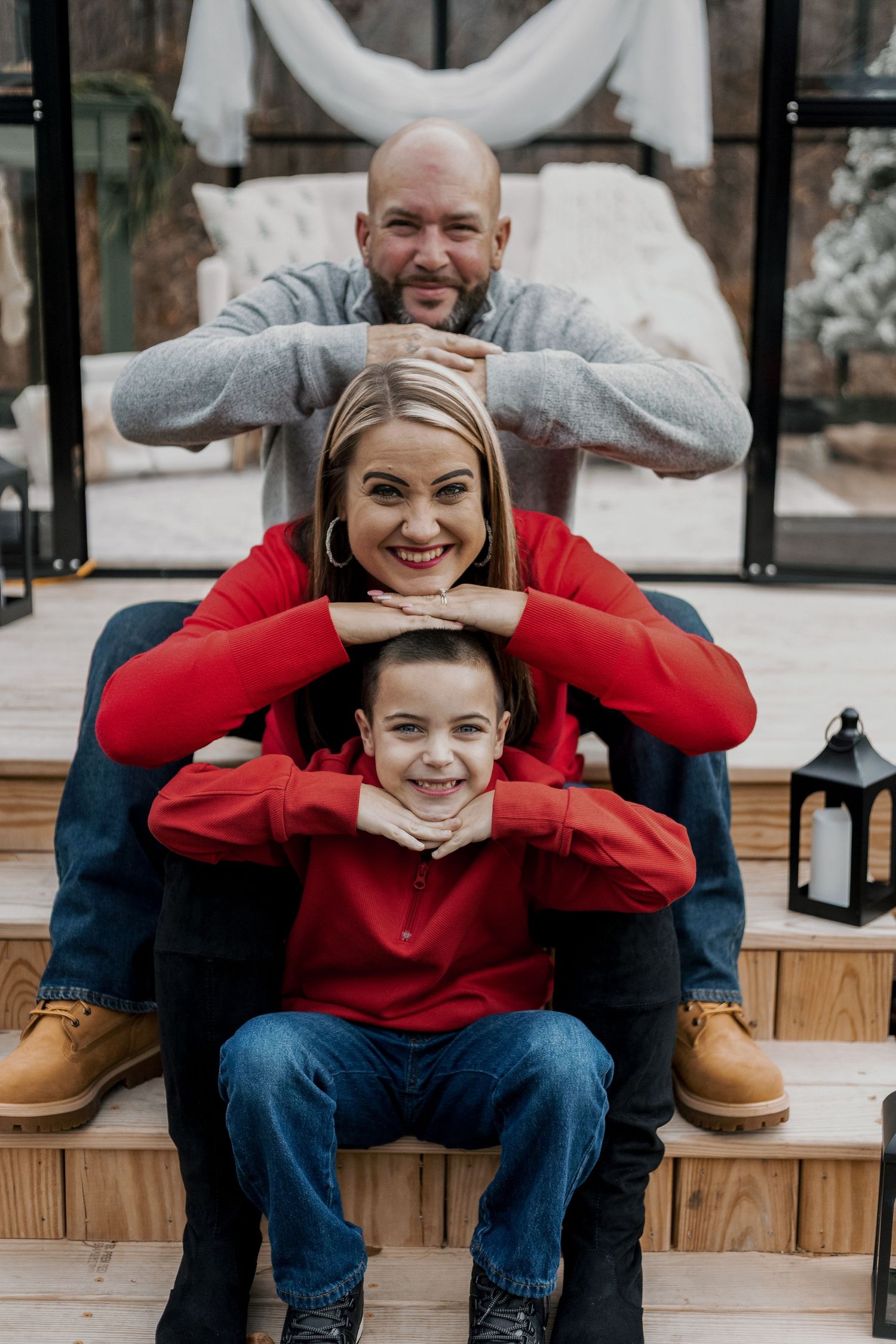 Fun family portrait session on wooden steps with coordinated red and blue outfits.