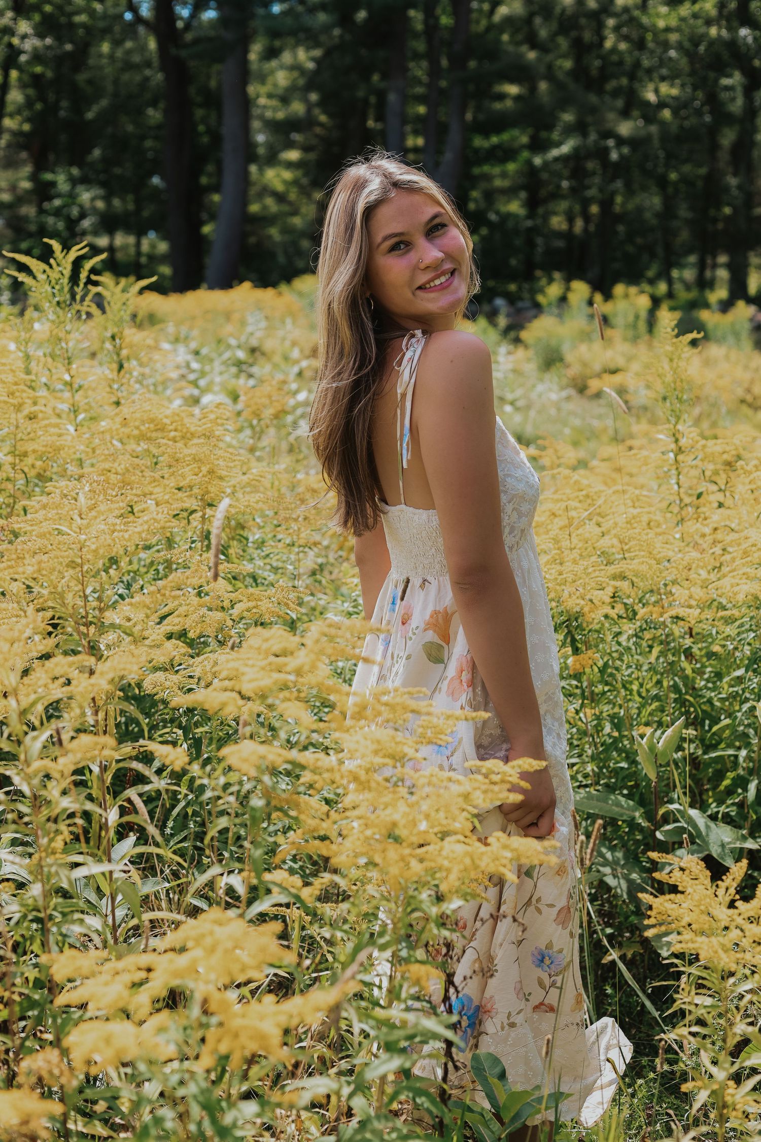 A floral dress catches the sunlight among yellow wildflowers in a natural outdoor setting.