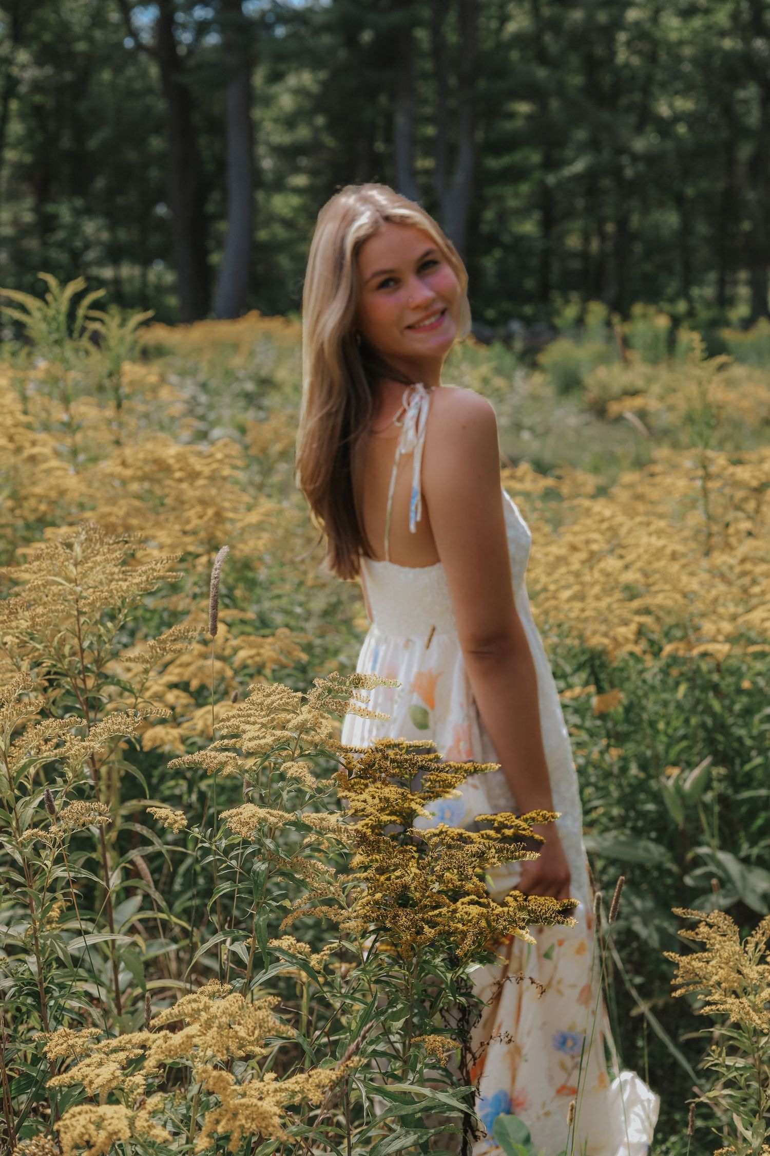 A white sundress contrasts beautifully against vibrant yellow flowers in a meadow setting.