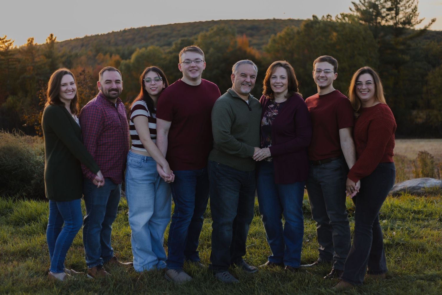 Multi-generational family portrait outdoors at sunset with mountains in the background.