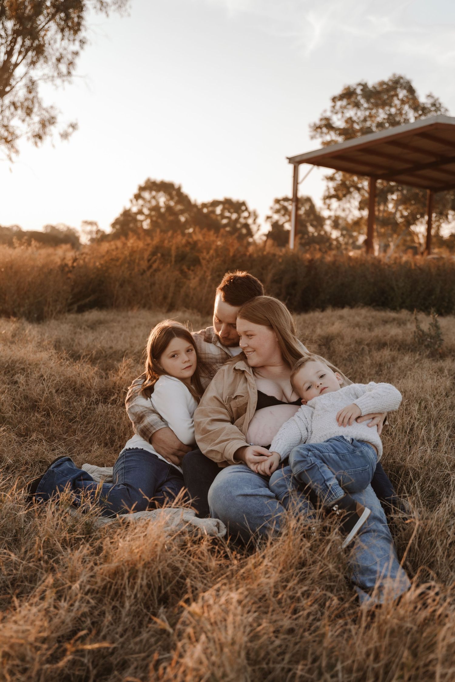 pregnant-mother-with-family-sitting-in-sunset-field-tongala
