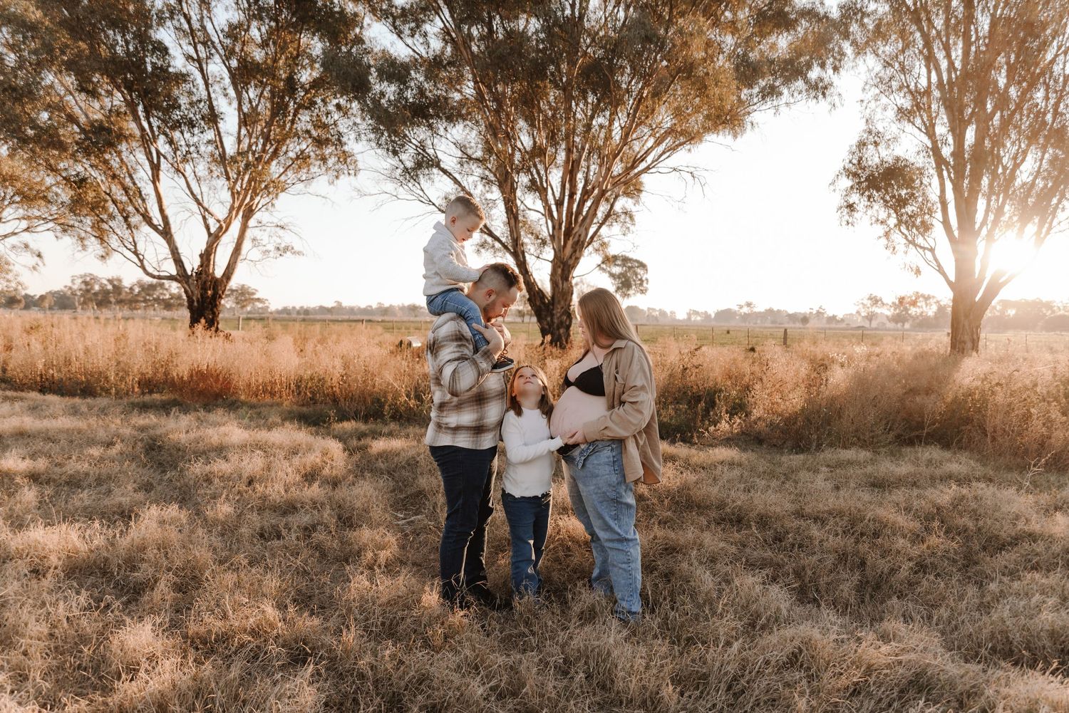 pregnant-mother-with-family-standing-in-sunset-field-tongala