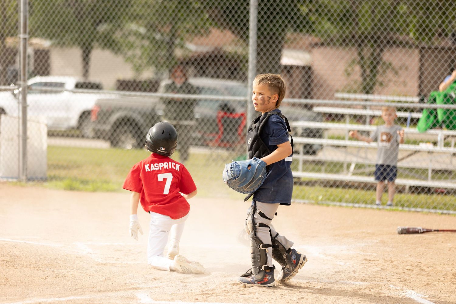 Two young boys playing little league baseball, catcher in gear and batter number 7 Kaprick at home plate.