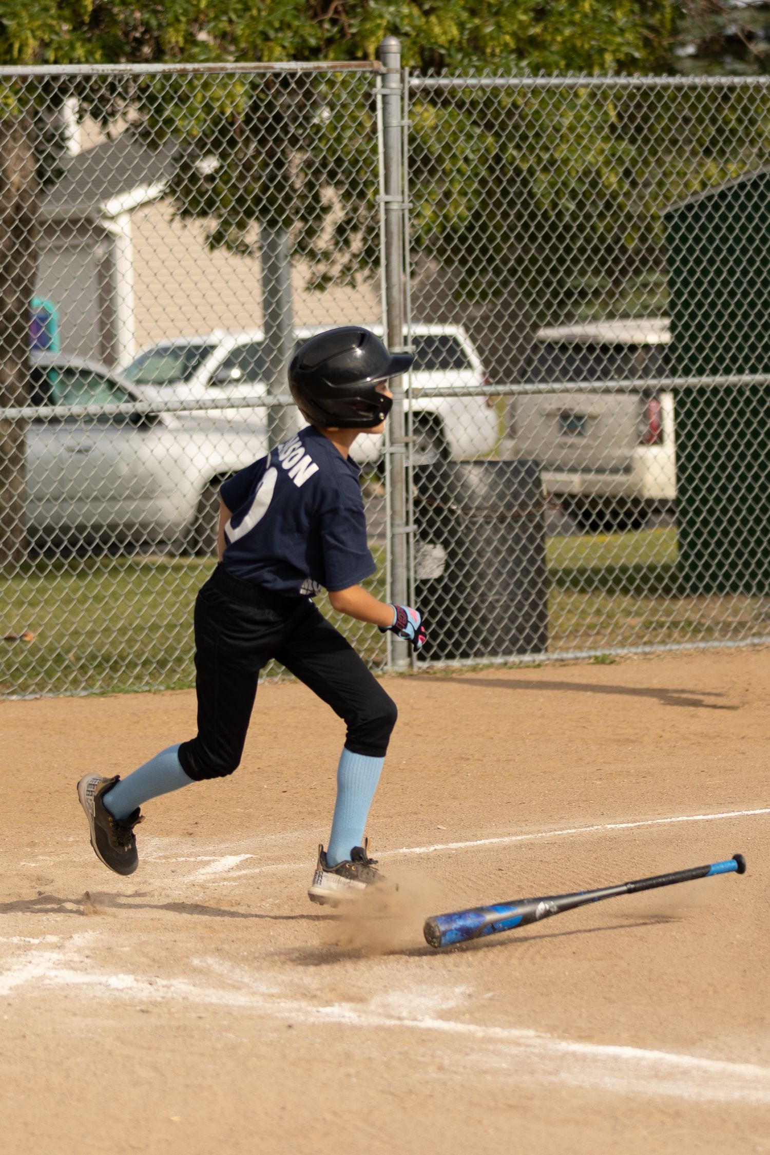 Young baseball player sprints toward first base after hitting the ball during a youth league game.
