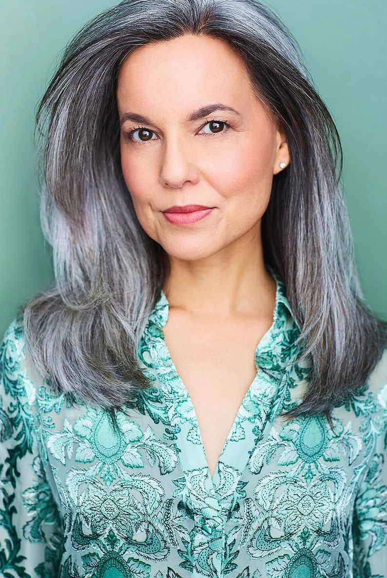 Corporate NYC headshot of a woman in a green blouse against a green background.