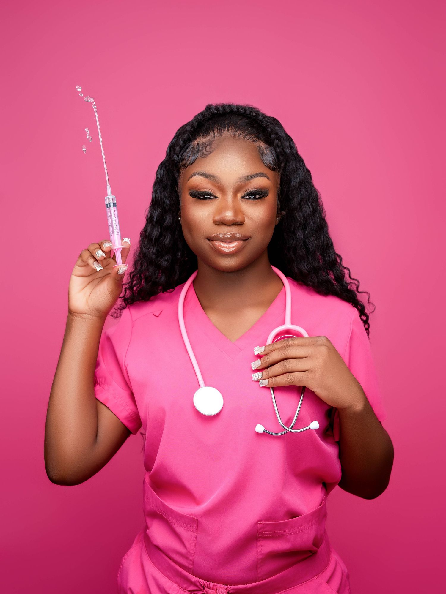 Healthcare professional in pink scrubs holding a syringe against vibrant pink background.