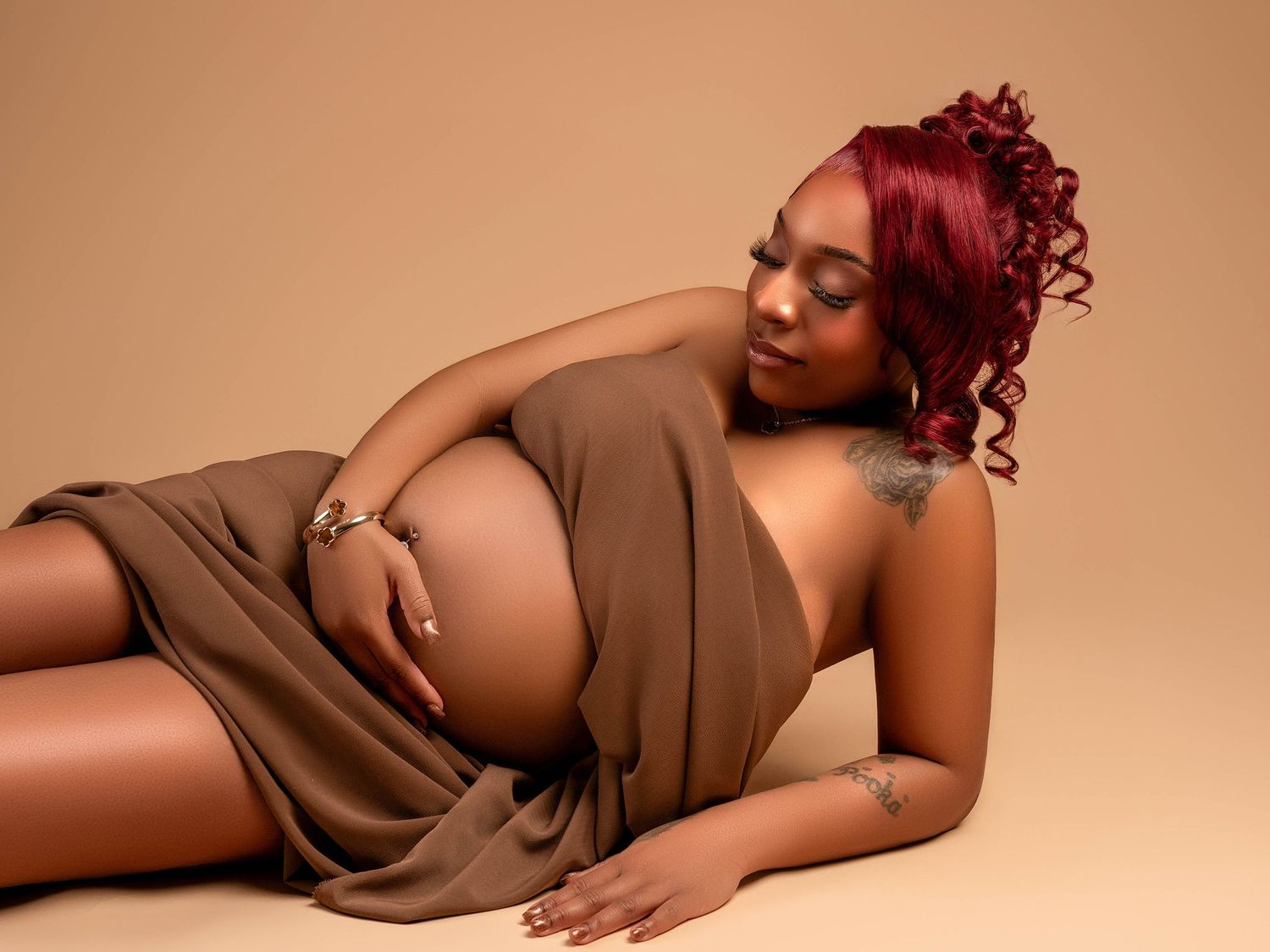 Artistic maternity portrait with subject in brown draping fabric.