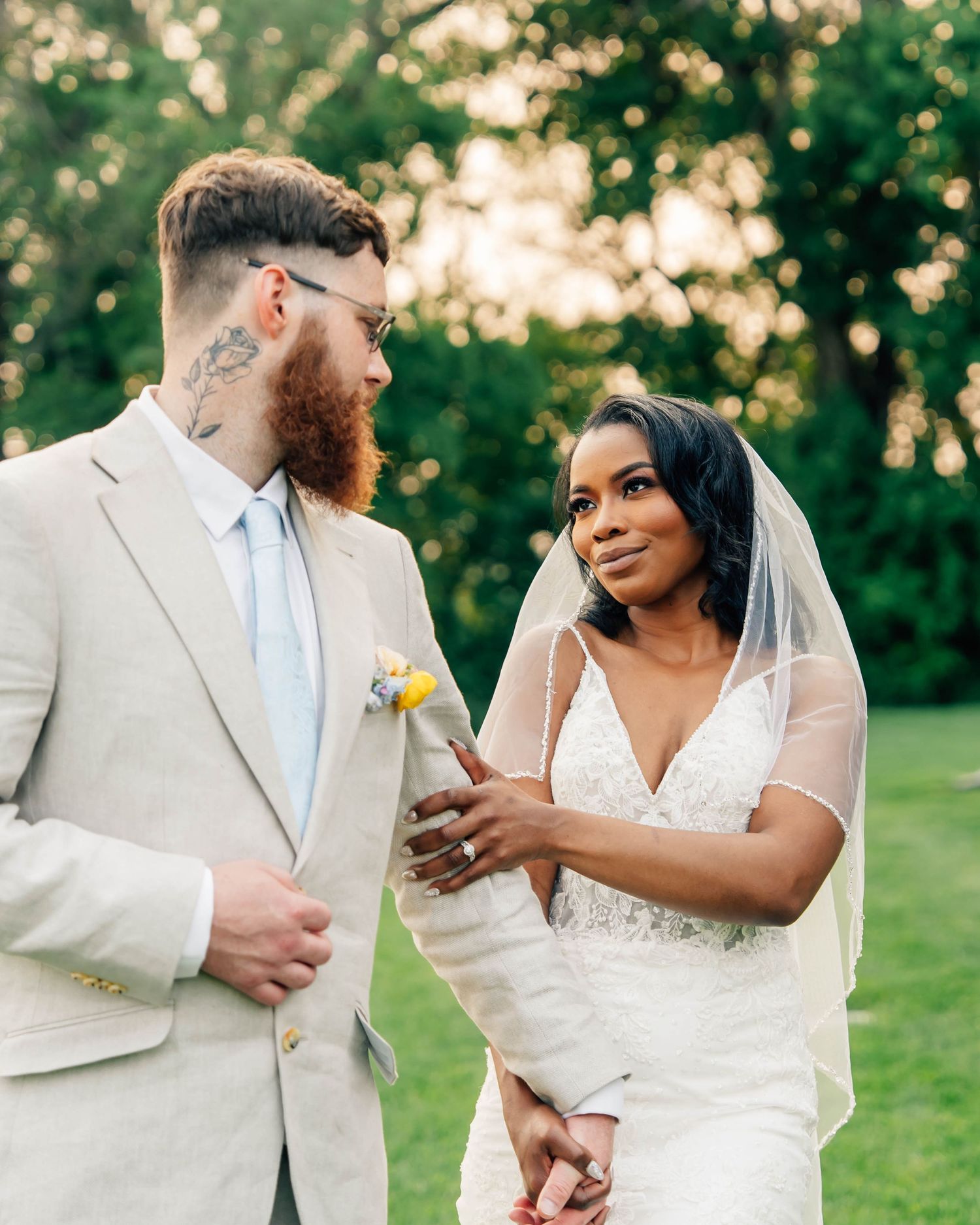 Romantic wedding couple shares intimate moments in a garden setting with flowing white dress and light gray suit.
