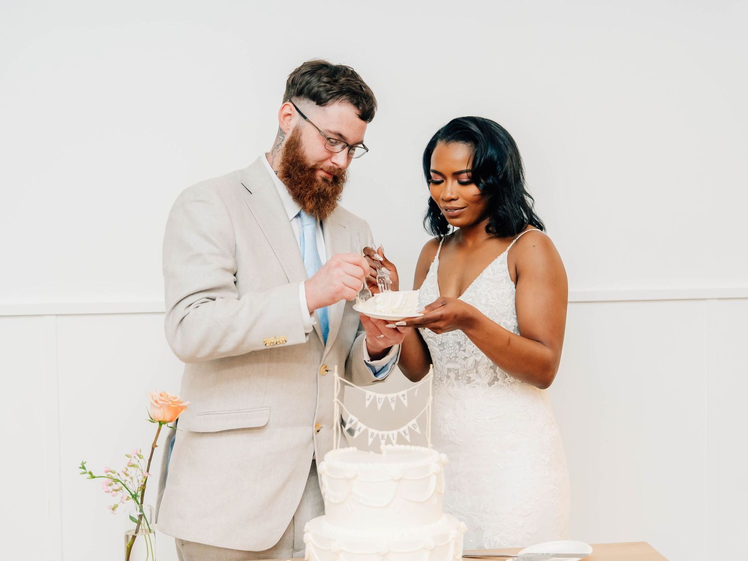 Newlyweds cutting their wedding cake together in modern minimalist setting.