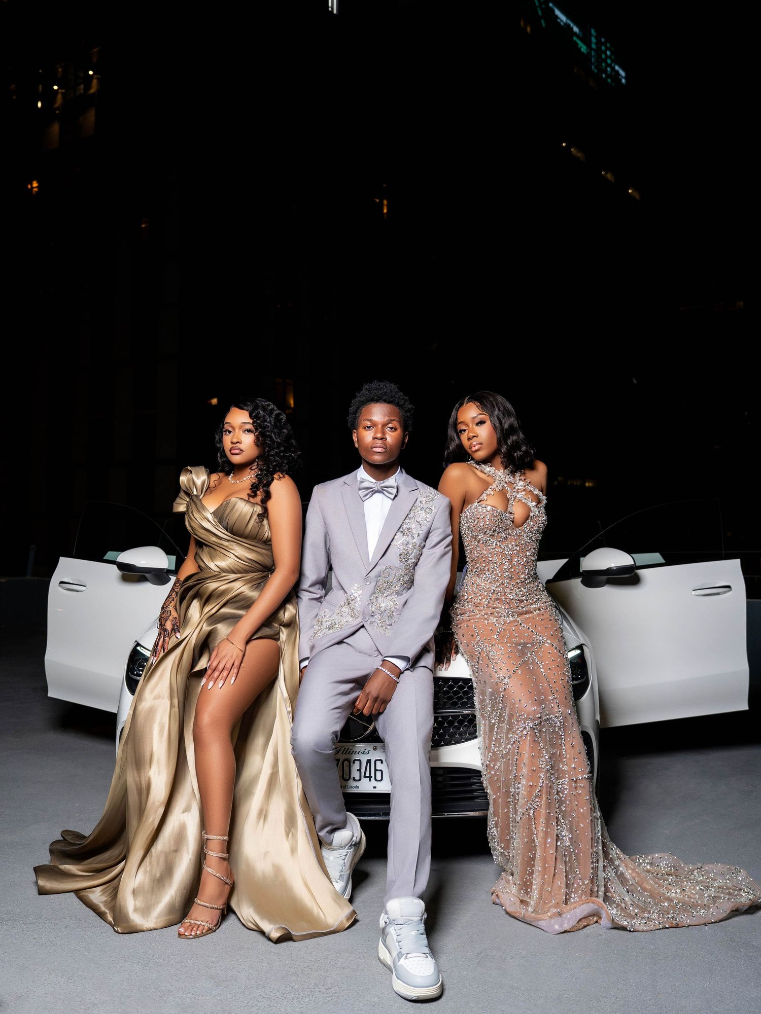 Elegant group photo with luxury car featuring formal attire in gold and silver evening wear.