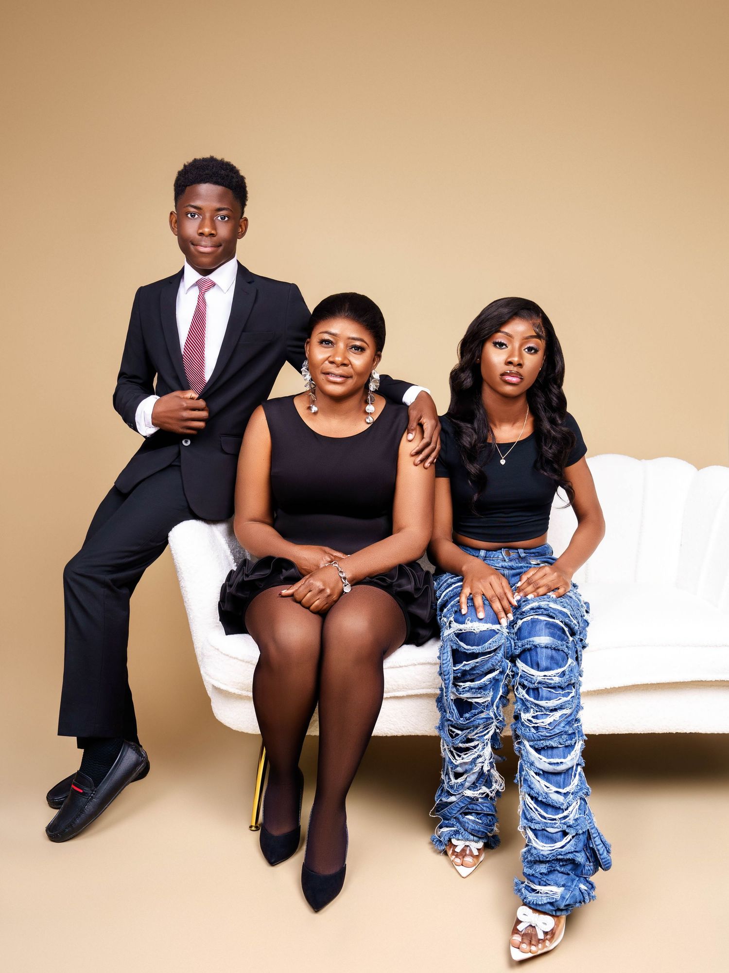 Stylish family portrait session with coordinated blue and black outfits against beige background.