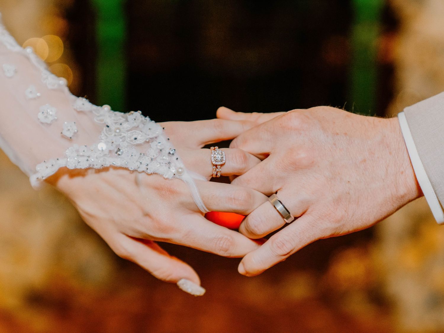 Close-up of hands exchanging wedding rings during ceremony.