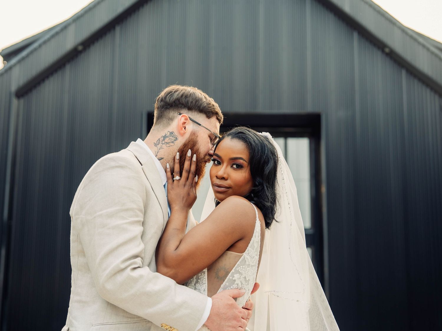 Candid wedding couple portraits against dark industrial building exterior.