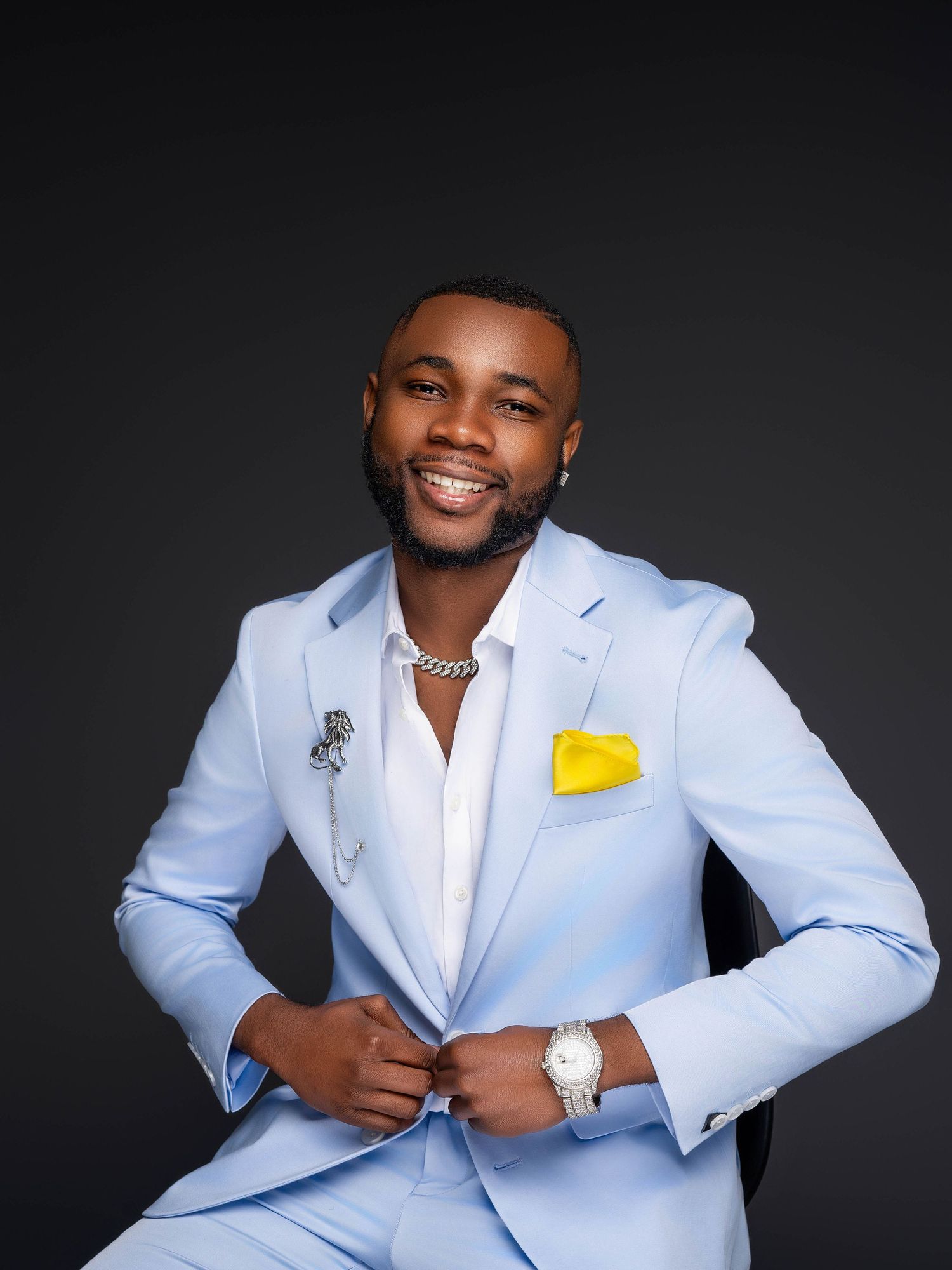 Professional headshots of man in light blue suit jacket against dark background.