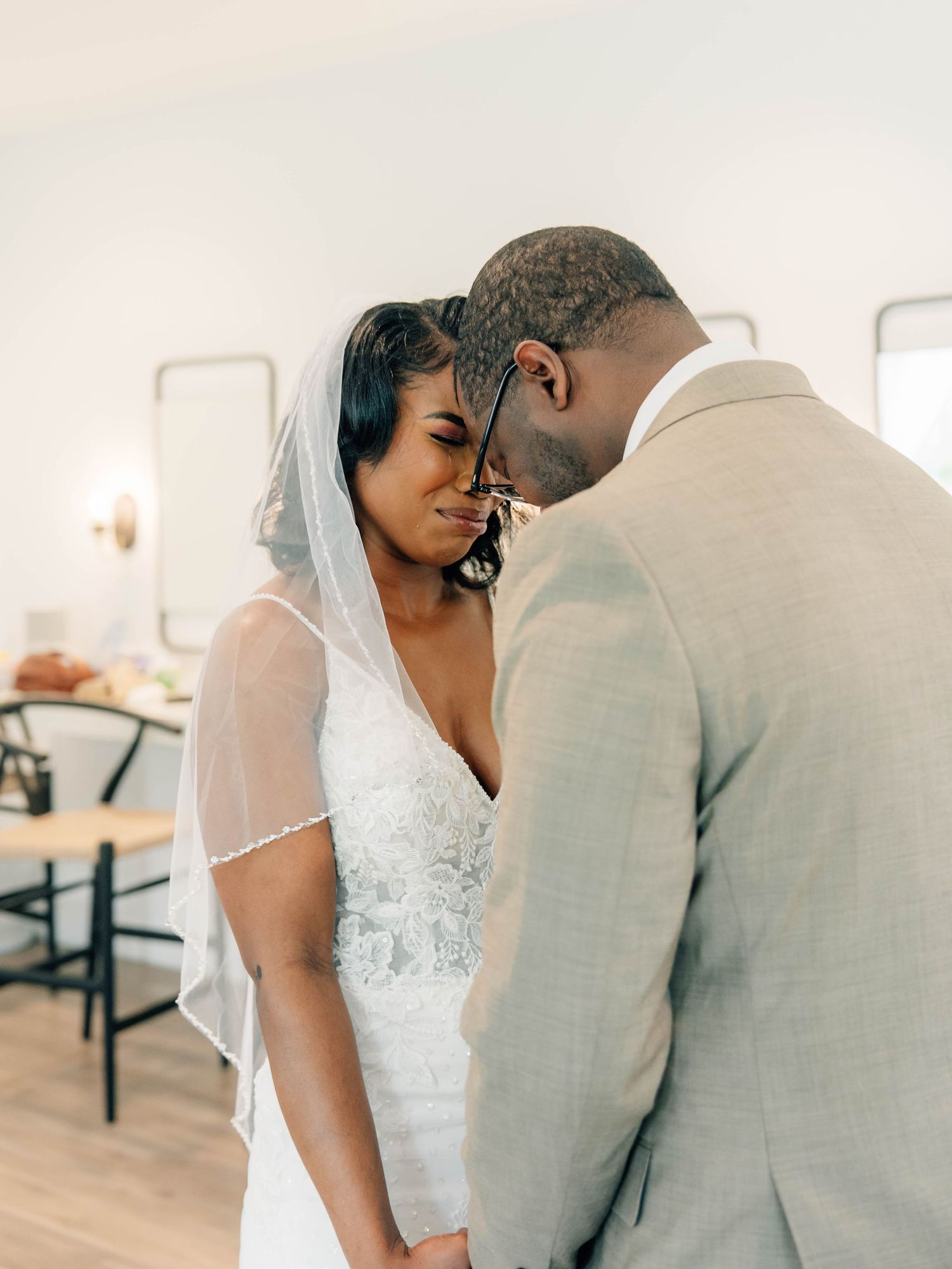Intimate wedding moment captured with couple in white dress and light grey suit touching foreheads.