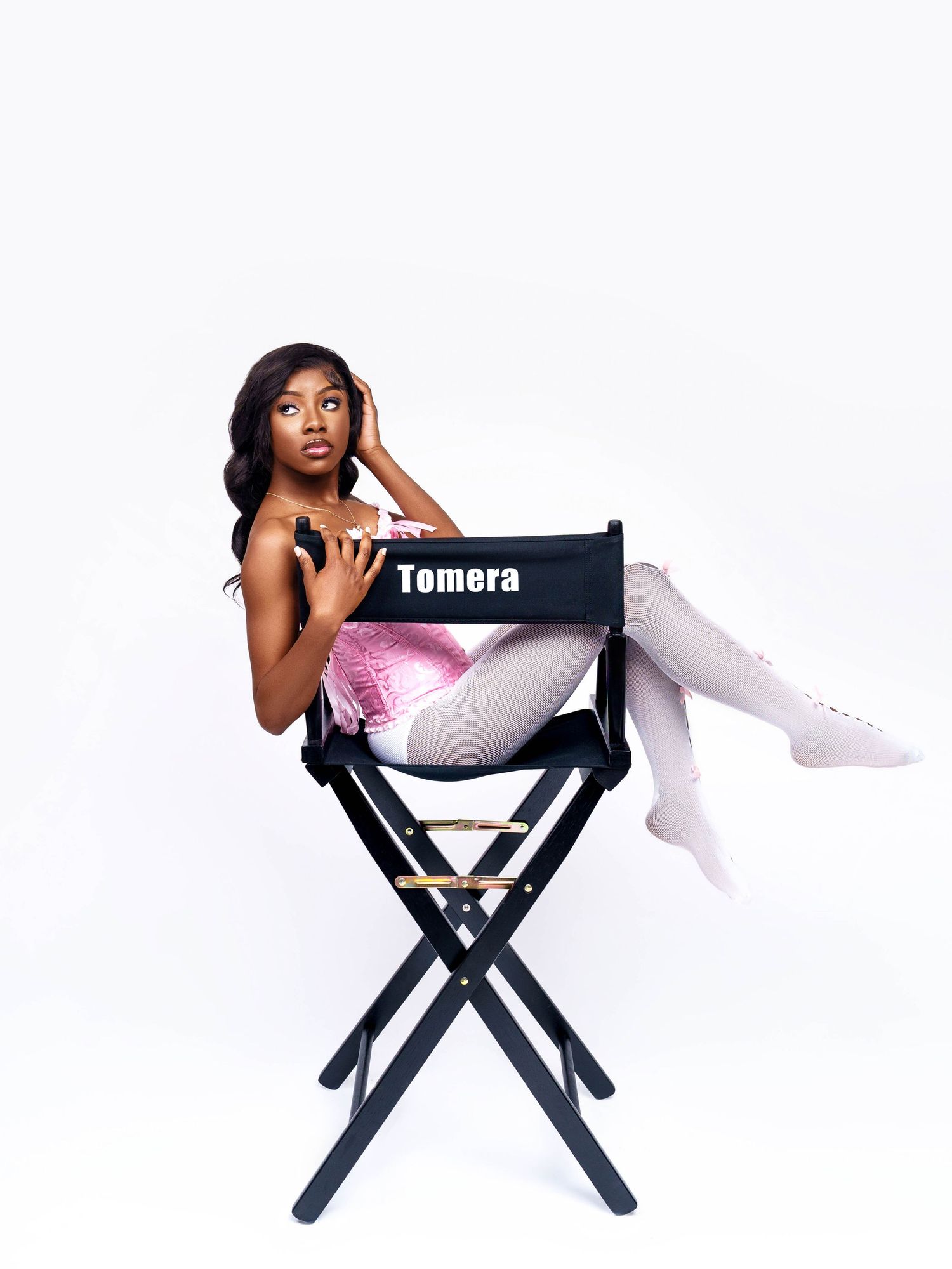 Artistic portrait featuring director's chair and white stockings in modern studio setting.