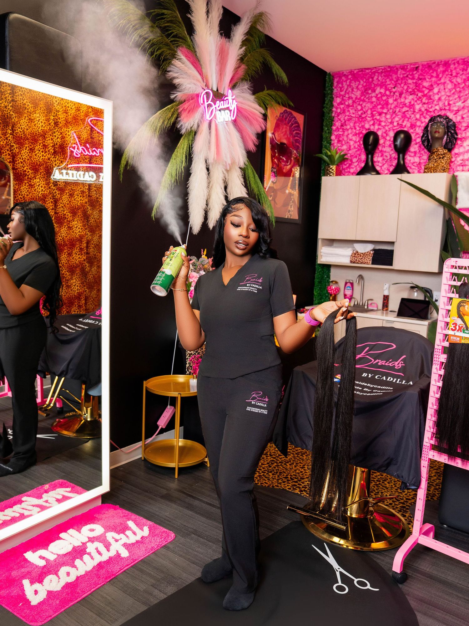 A salon professional poses with styling tools in a vibrant pink and black beauty salon interior.