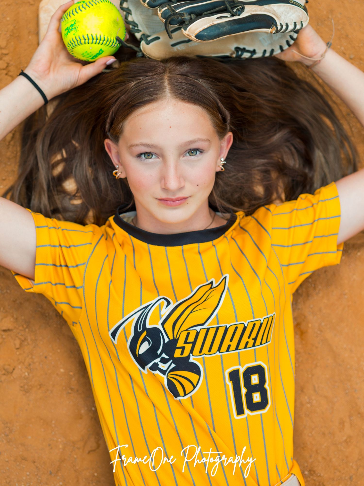 Softball senior portrait composite showing three poses of athlete in yellow striped uniform laying on orange dirt field.