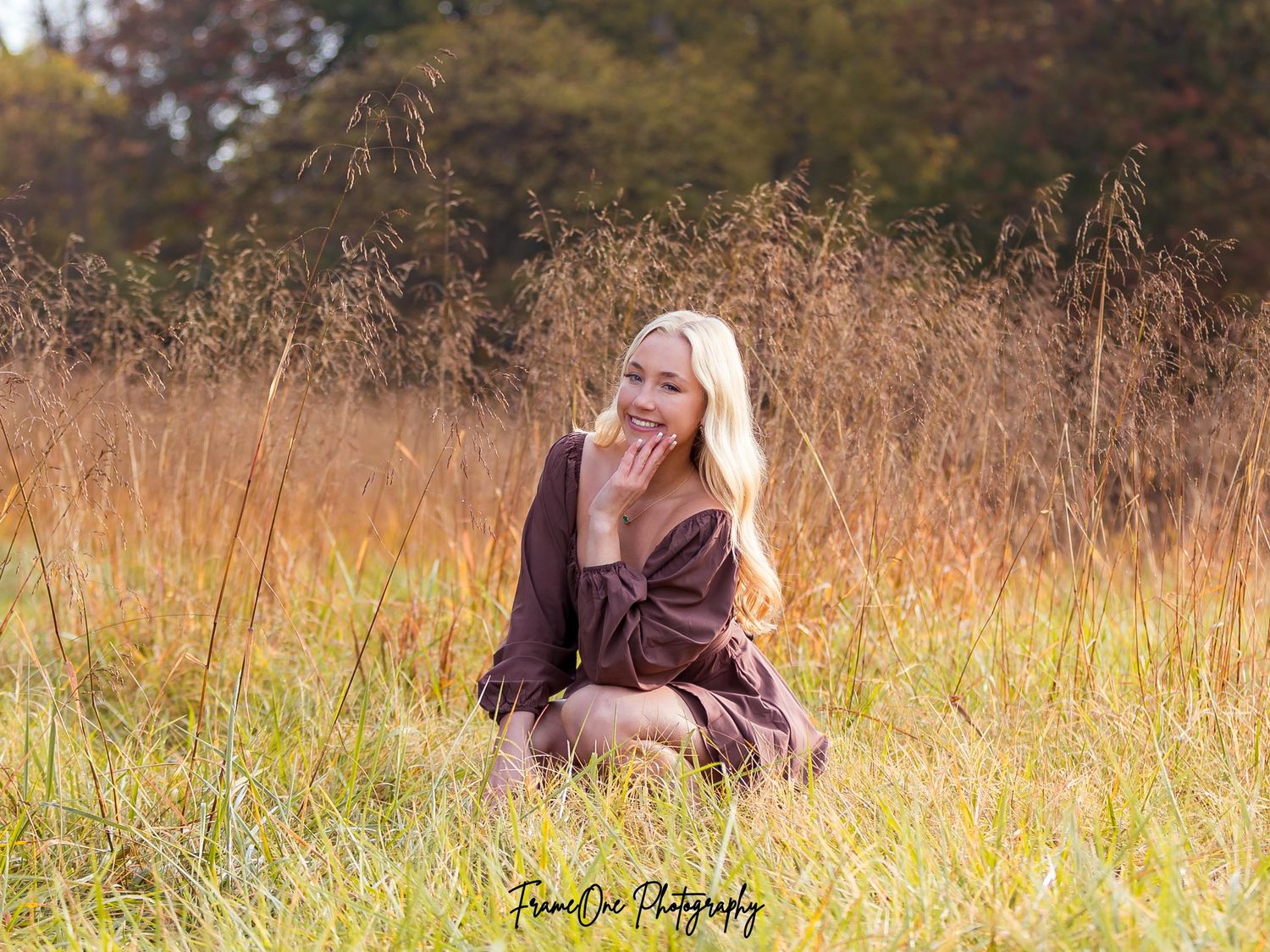 A couple sits together in a golden autumn field during a romantic outdoor photography session.