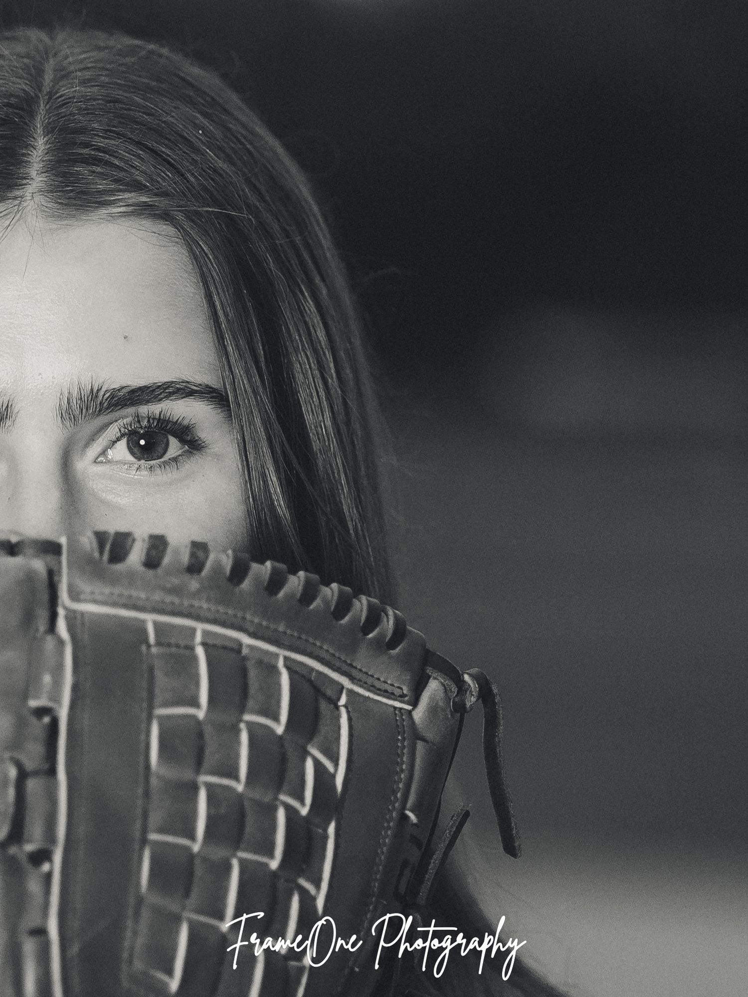 Creative black and white sports portrait showing baseball glove and partial view, with shallow depth of field details.