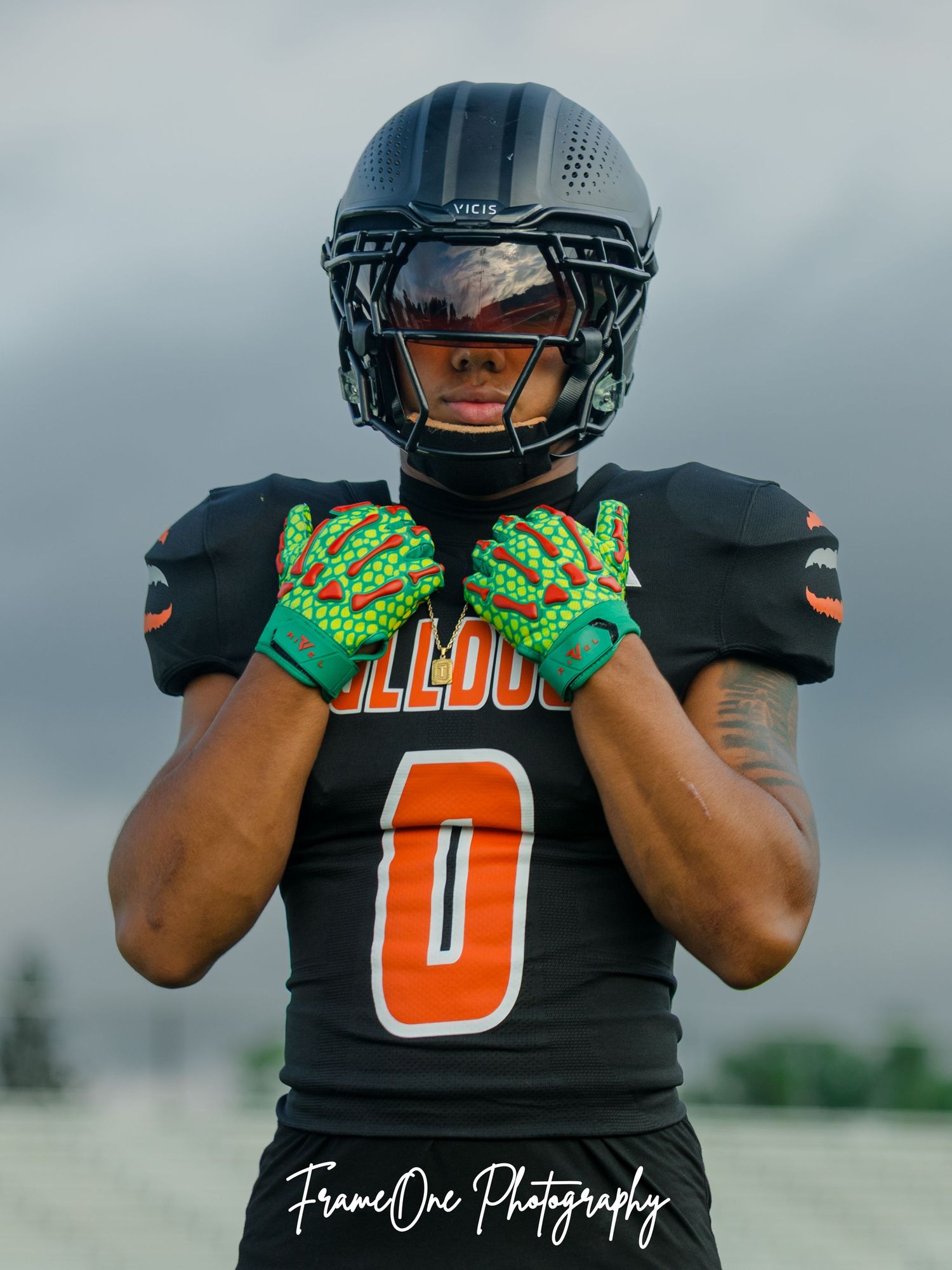 Close up of black and orange football jersey showing the number 0 with green and orange glove details on overcast day.