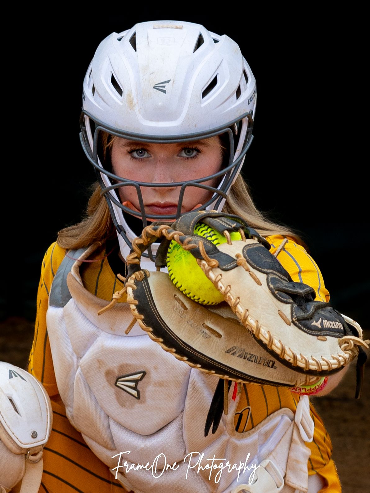 Softball player wearing white helmet and yellow uniform holds up catcher's mitt in series of progressive action shots.