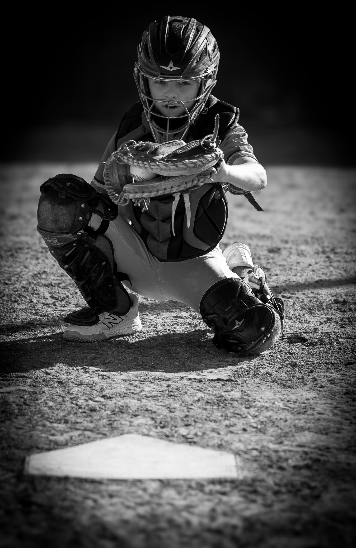 Black and white close-up shots of a baseball catcher crouching at home plate.