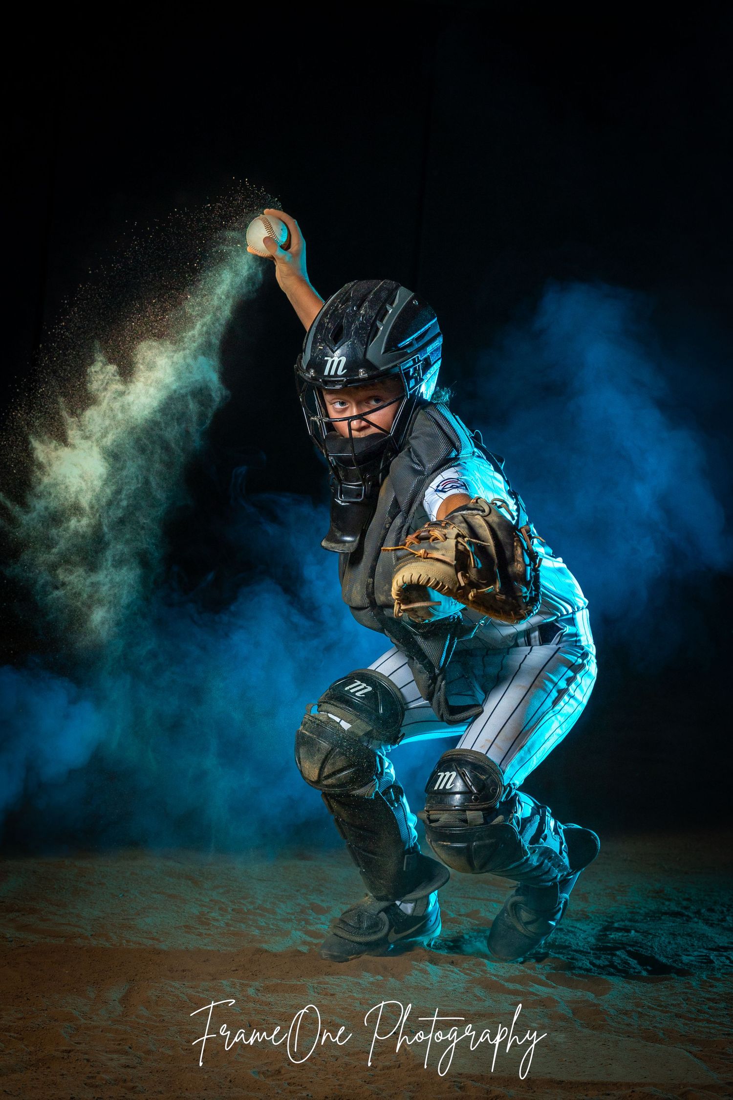 Baseball player in protective gear poses dynamically against dramatic blue and green smoke on dark background.