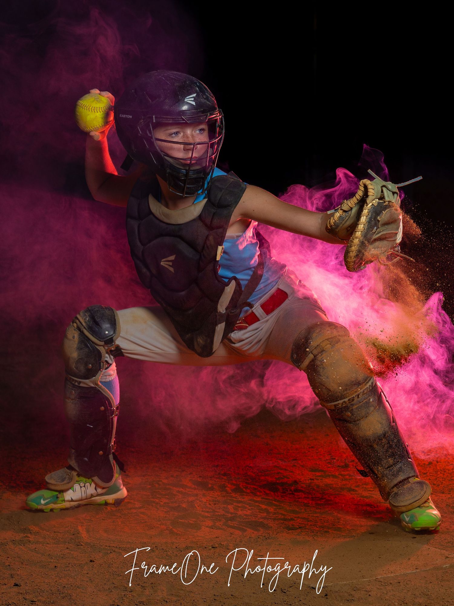 Softball player sliding into base with pink smoke effects and dirt creating dramatic action shot.