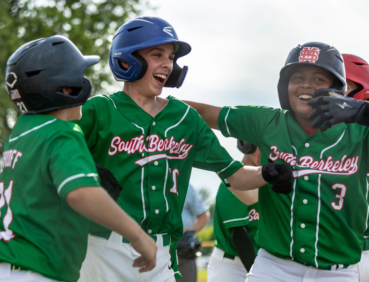Baseball players in green jerseys celebrate enthusiastically during a game.