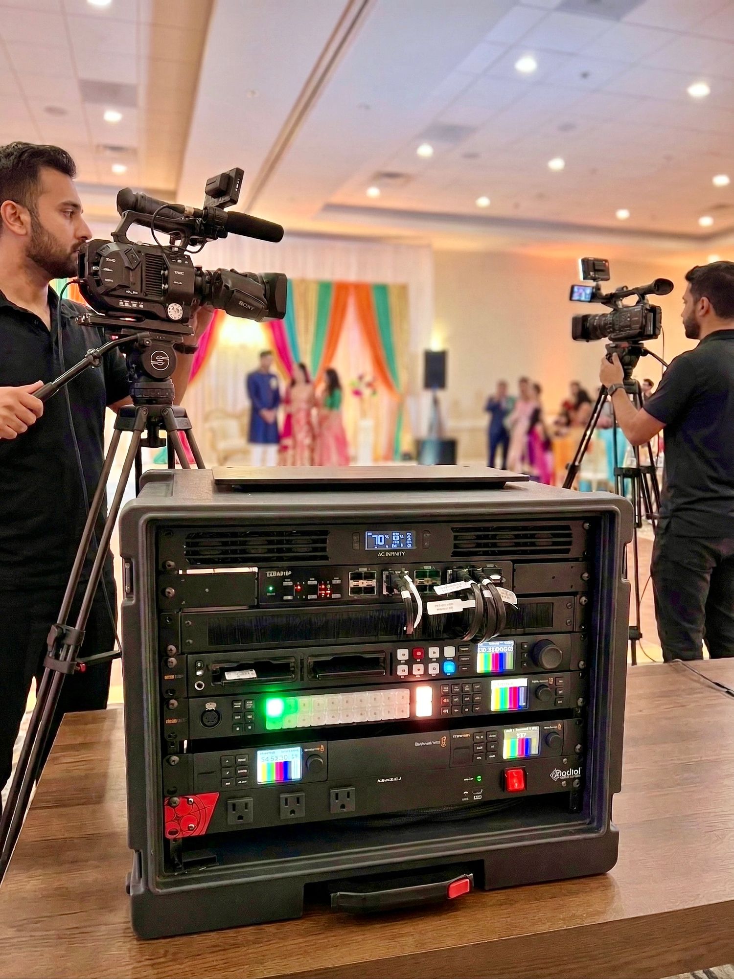 Professional video production equipment setup showing multiple camera monitors and control panels at an indoor event venue.