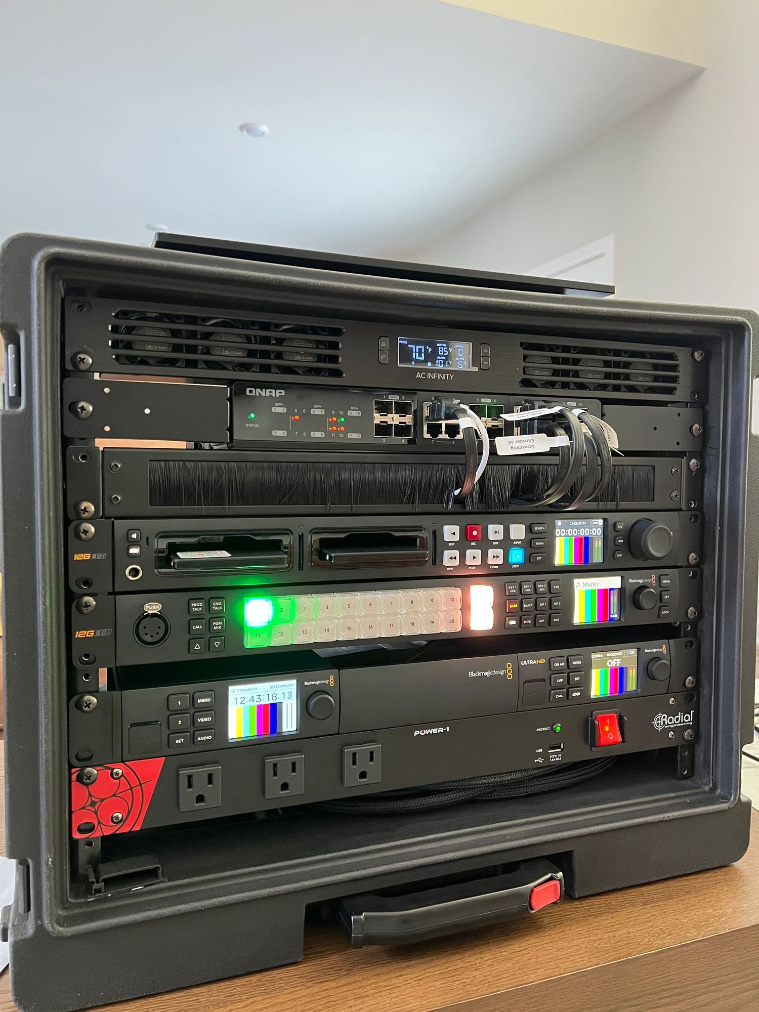 Professional audio equipment rack with multiple electronic devices and LED displays mounted in a portable road case.