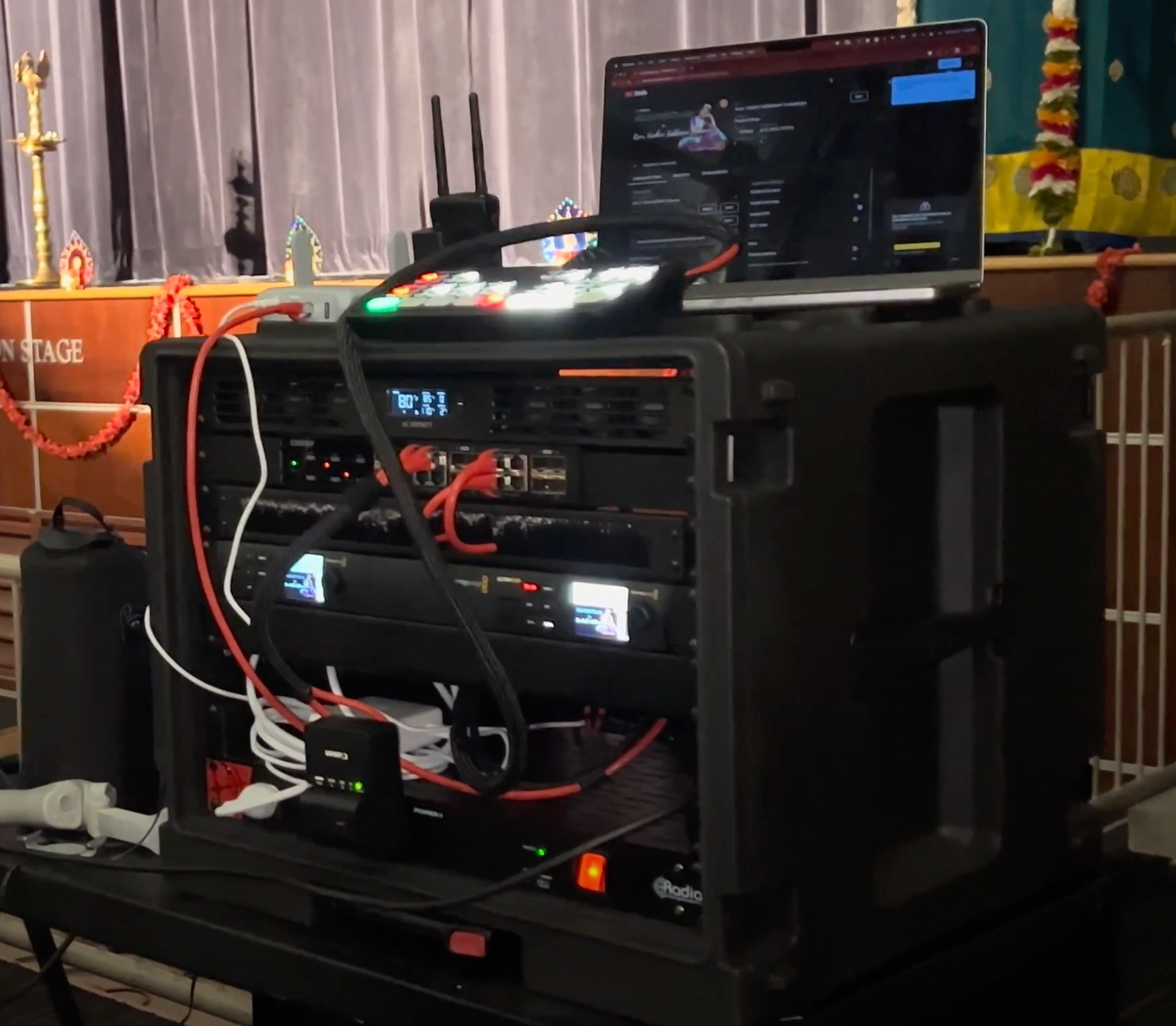 Professional audio rack setup with multiple components and cables connected to equipment in a black rack enclosure.
