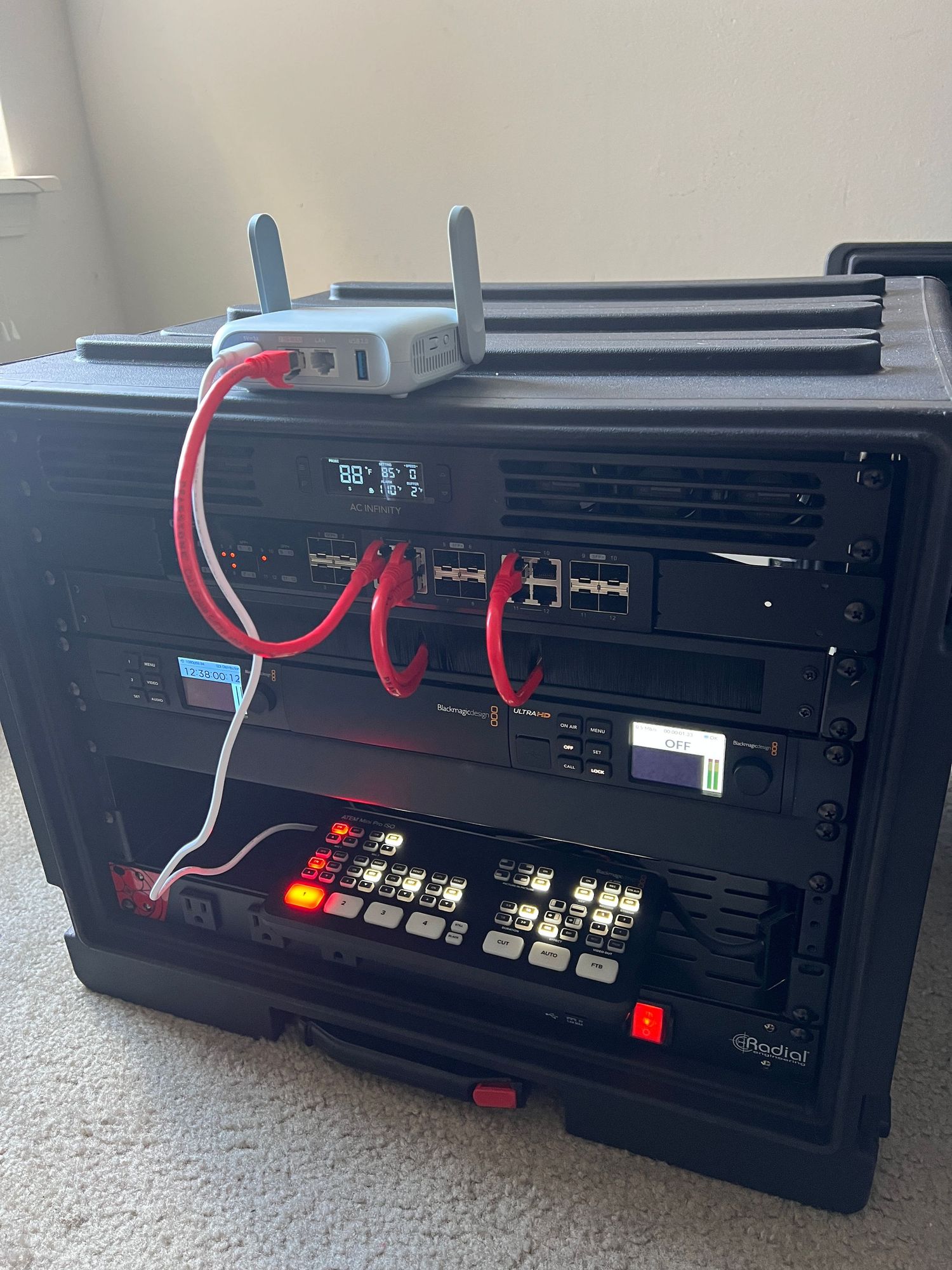 Network rack setup showing black equipment chassis with red cable connections and control panel buttons.