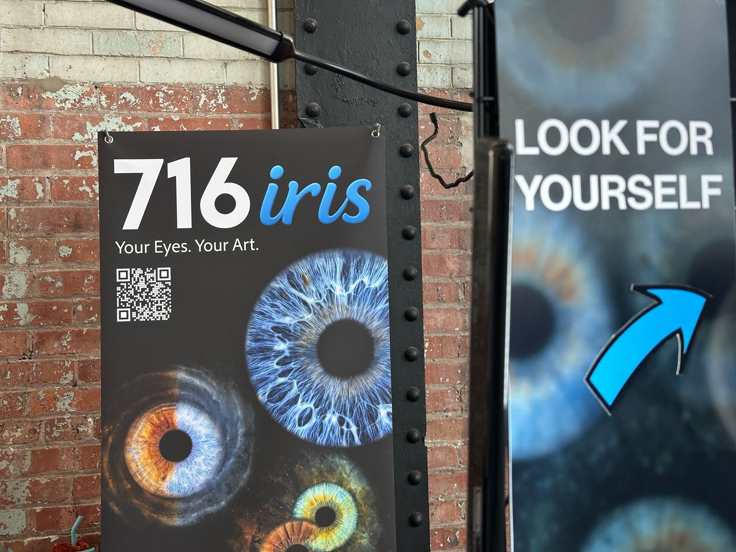 716 Iris eye art studio advertisement sign on brick wall featuring colorful iris photography and QR code.