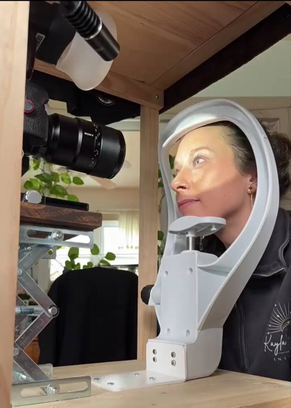 A white robotic photography stand with camera equipment mounted overhead captures a studio portrait setup.
