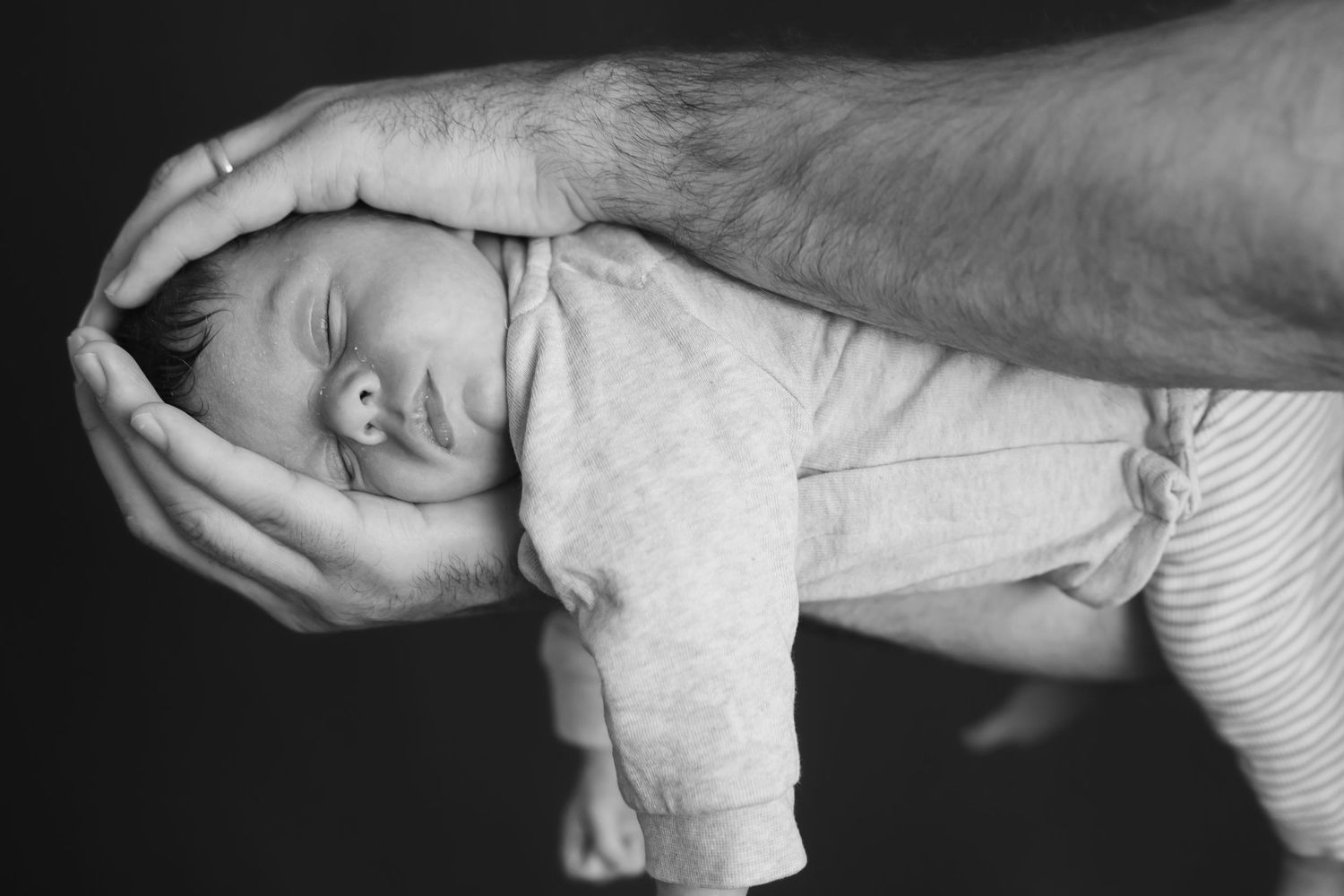 Newborn Fotograf Berlin – Nahaufnahme von Baby  von Eltern gehalten wird, schwarz-weiß Babyfotografie Homestory, The Elephant Lab