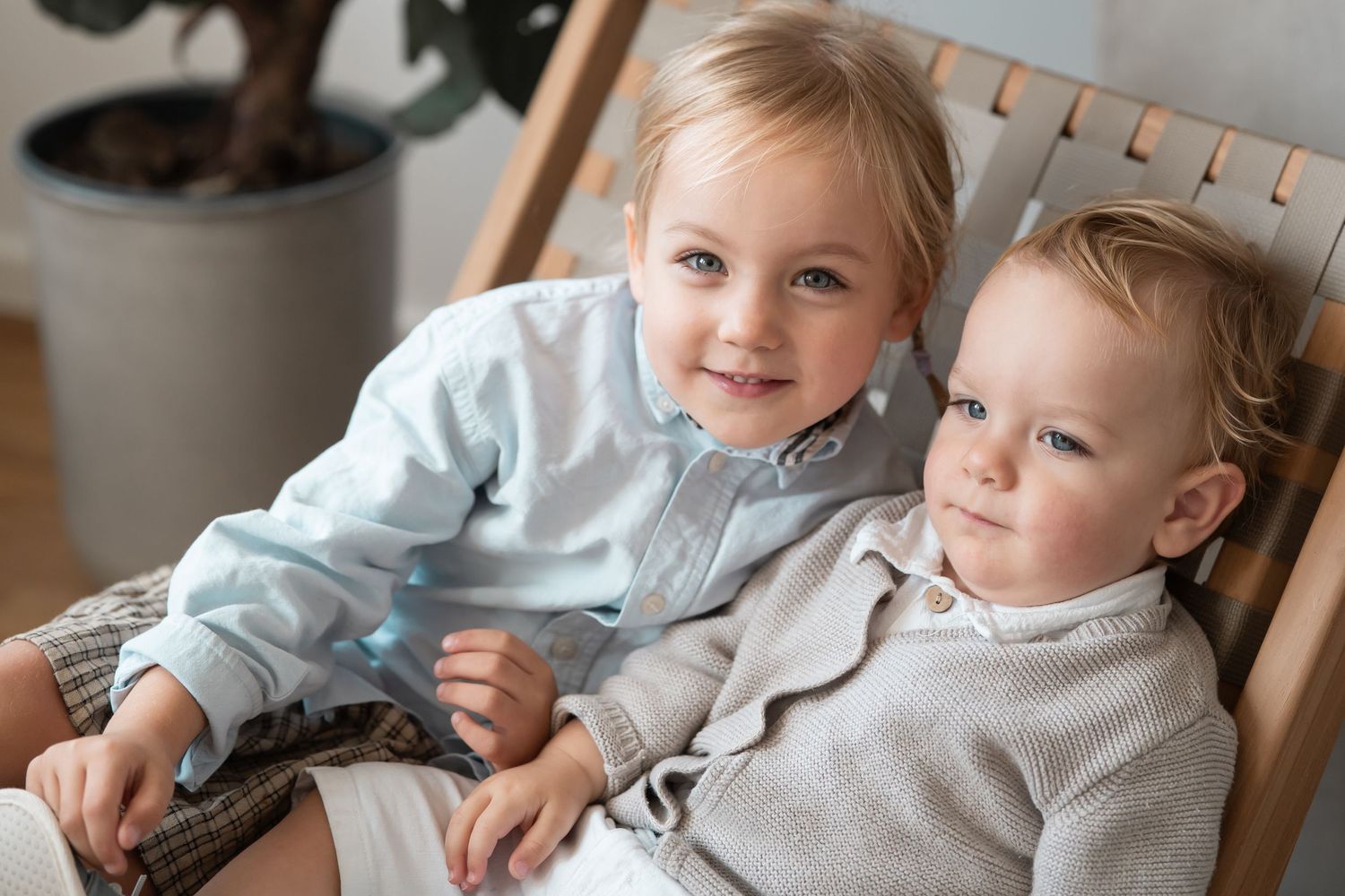 Zwei kleine Geschwister sitzen nah beieinander bei einem liebevollen Kinder Fotoshooting in hellem natürlichen studio Licht